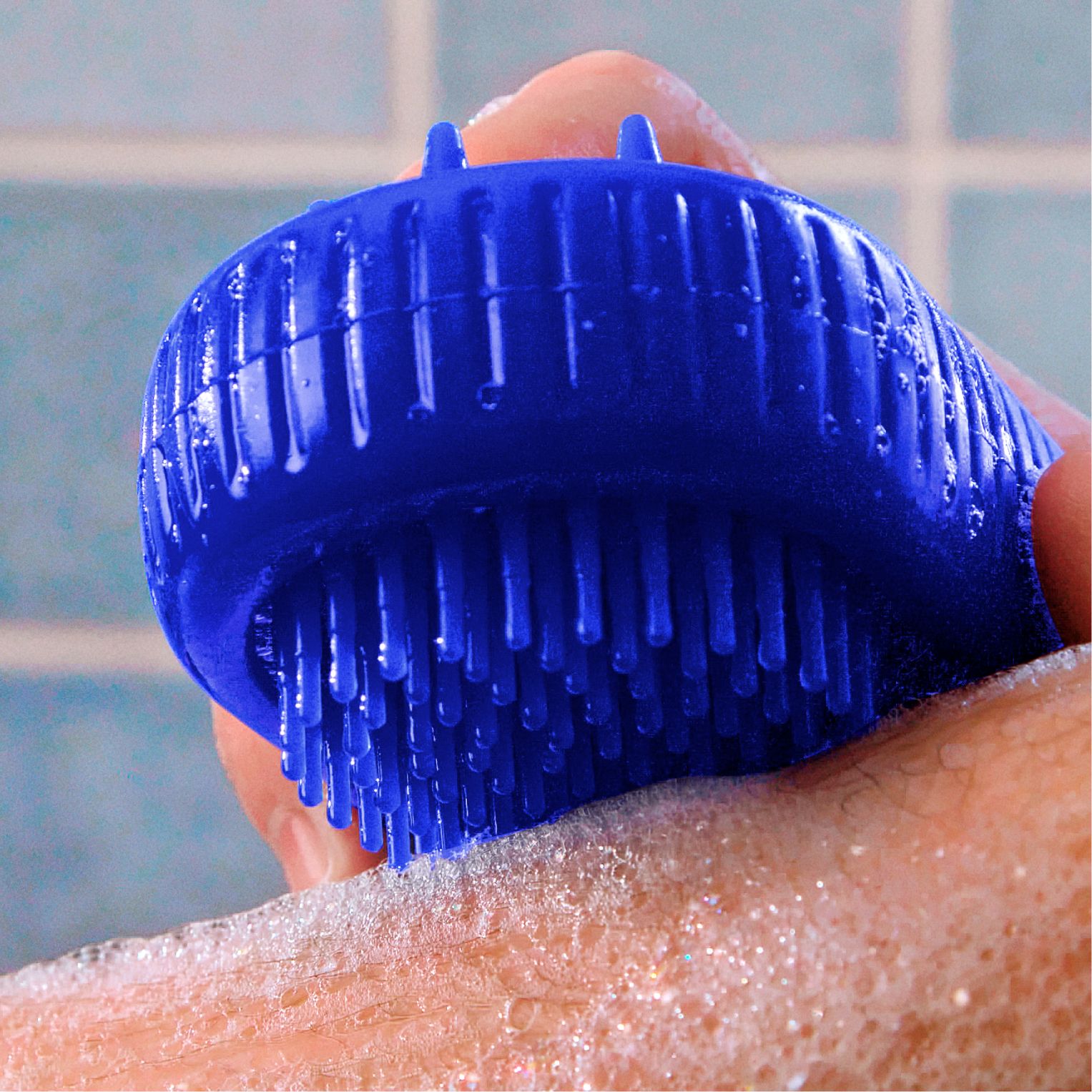 Blue scrubber on soapy arm, close up view, with out of focus blue tile background