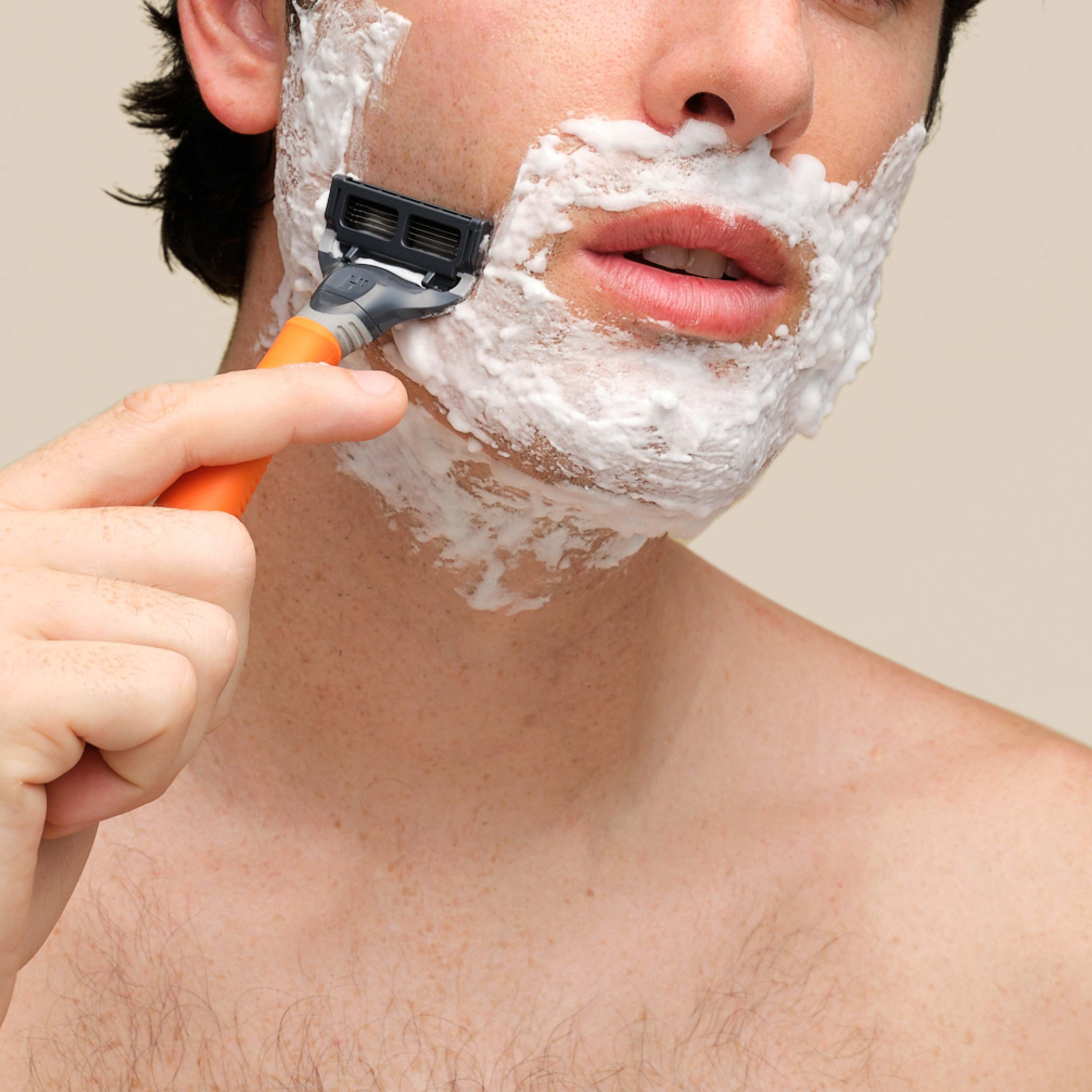 Man using Shave Gel and the Original Razor to shave his cheek.