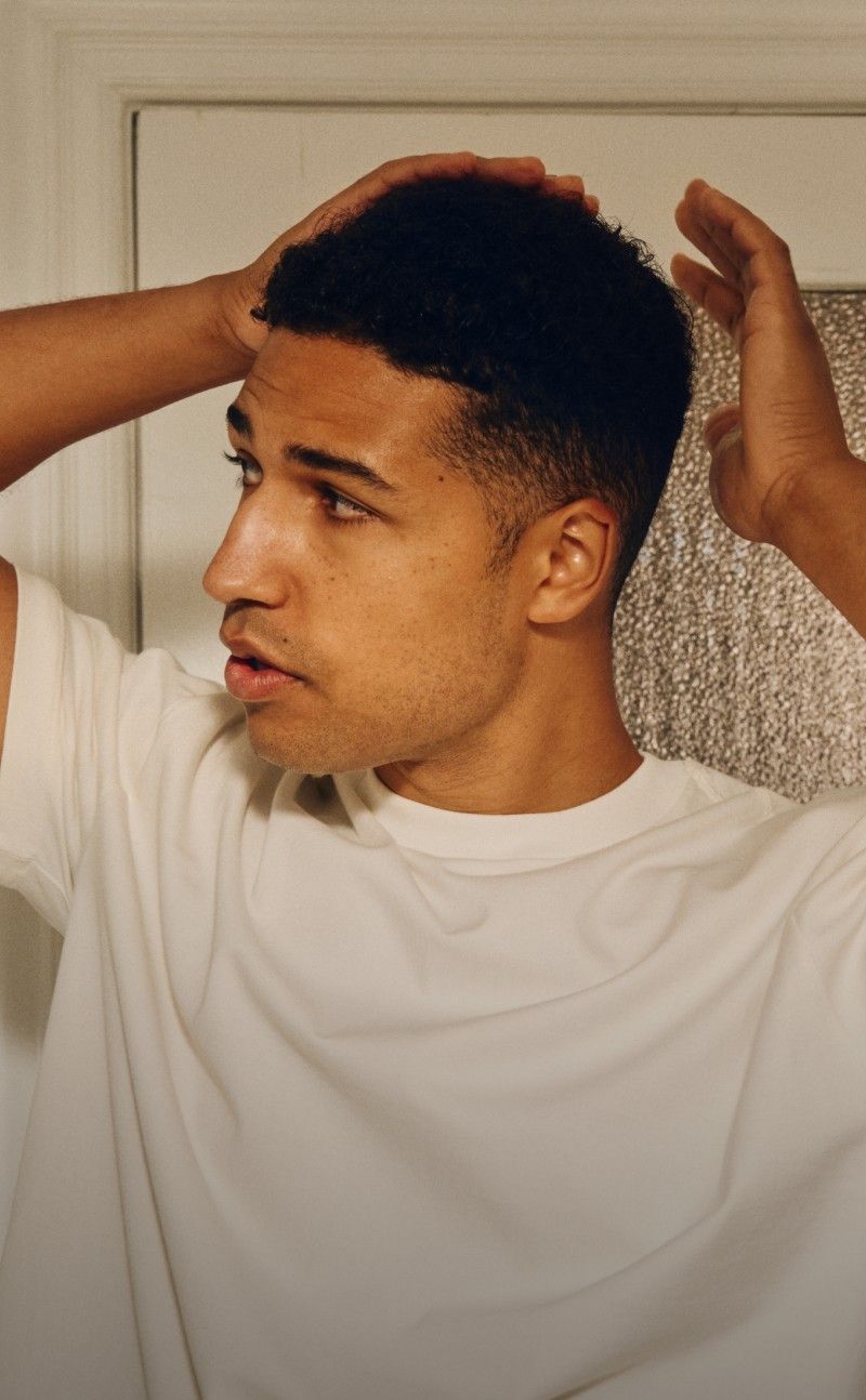 Person applying product to hair in a bathroom setting
