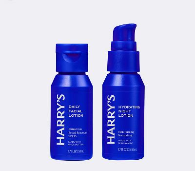 Blue bottles of face care products that have white next on them against a grey background