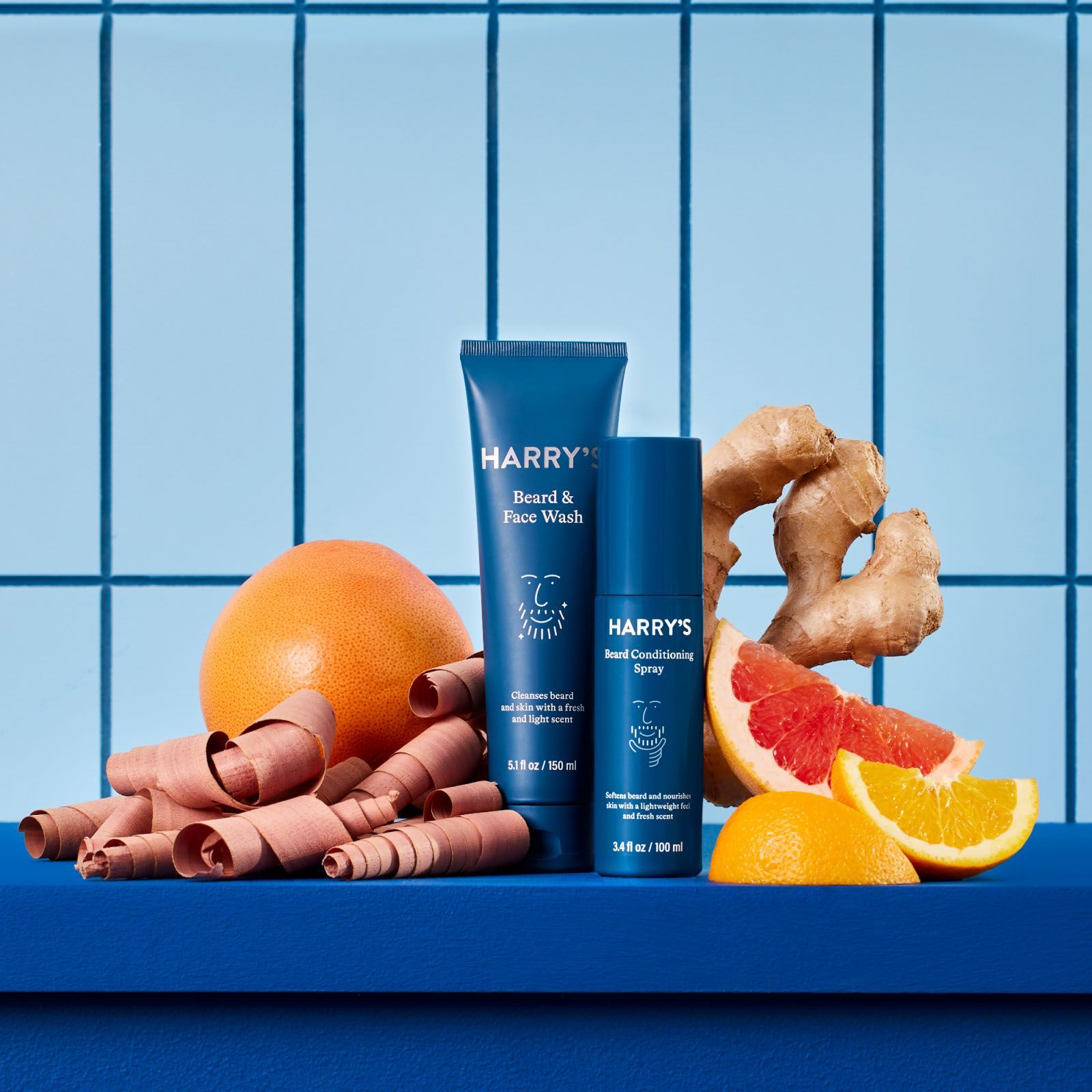 Beard and Face Wash next to the Beard Conditioning Spray, surrounded citrus fruits and fresh ginger.