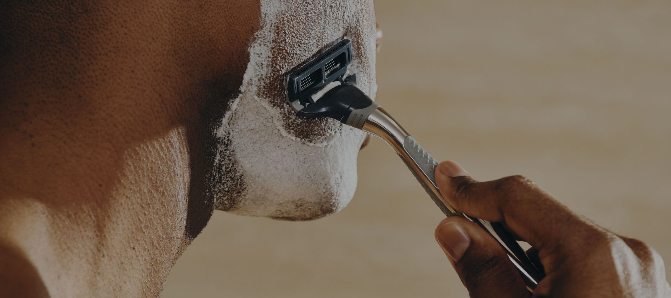 A view from the side of a man shaving his face in a bathroom