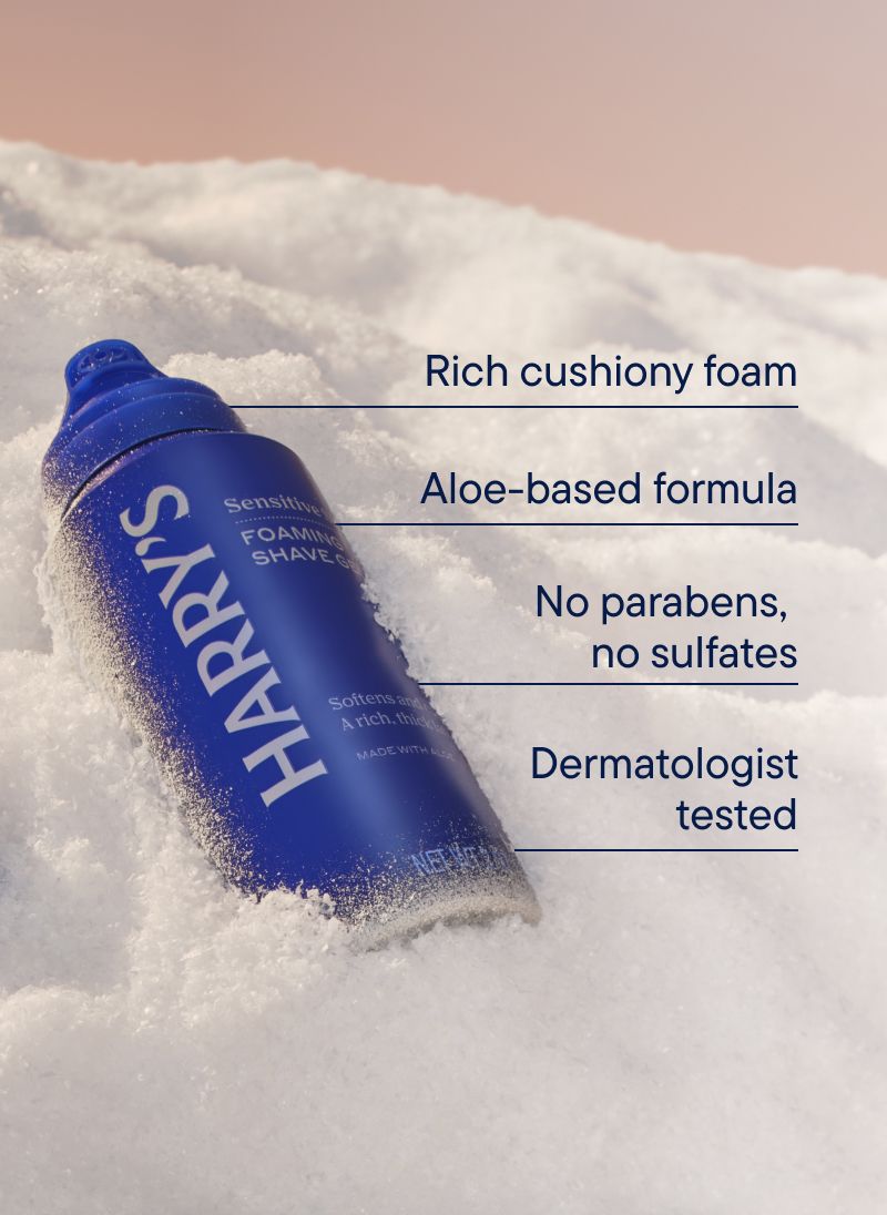 A blue can of Foaming Shave Gel with the cap off in a bank of snow with text describing how it has cushiony foam, aloe-based formula, and is dermatologist tested