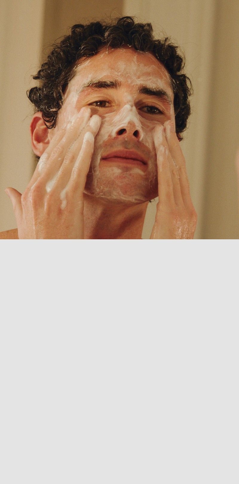 Man applying face wash to his face with a blurred background.