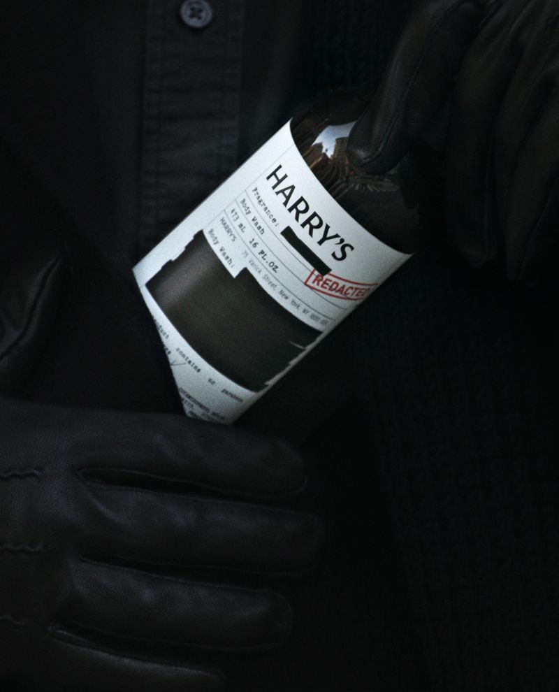 Black gloves holding Harry's redacted Body Wash bottle