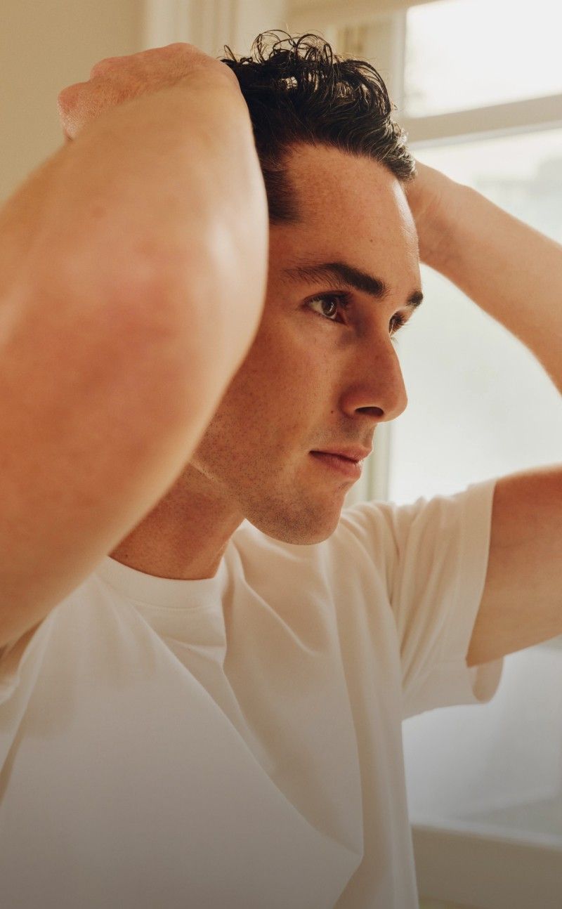 Person applying product to hair in a bathroom setting