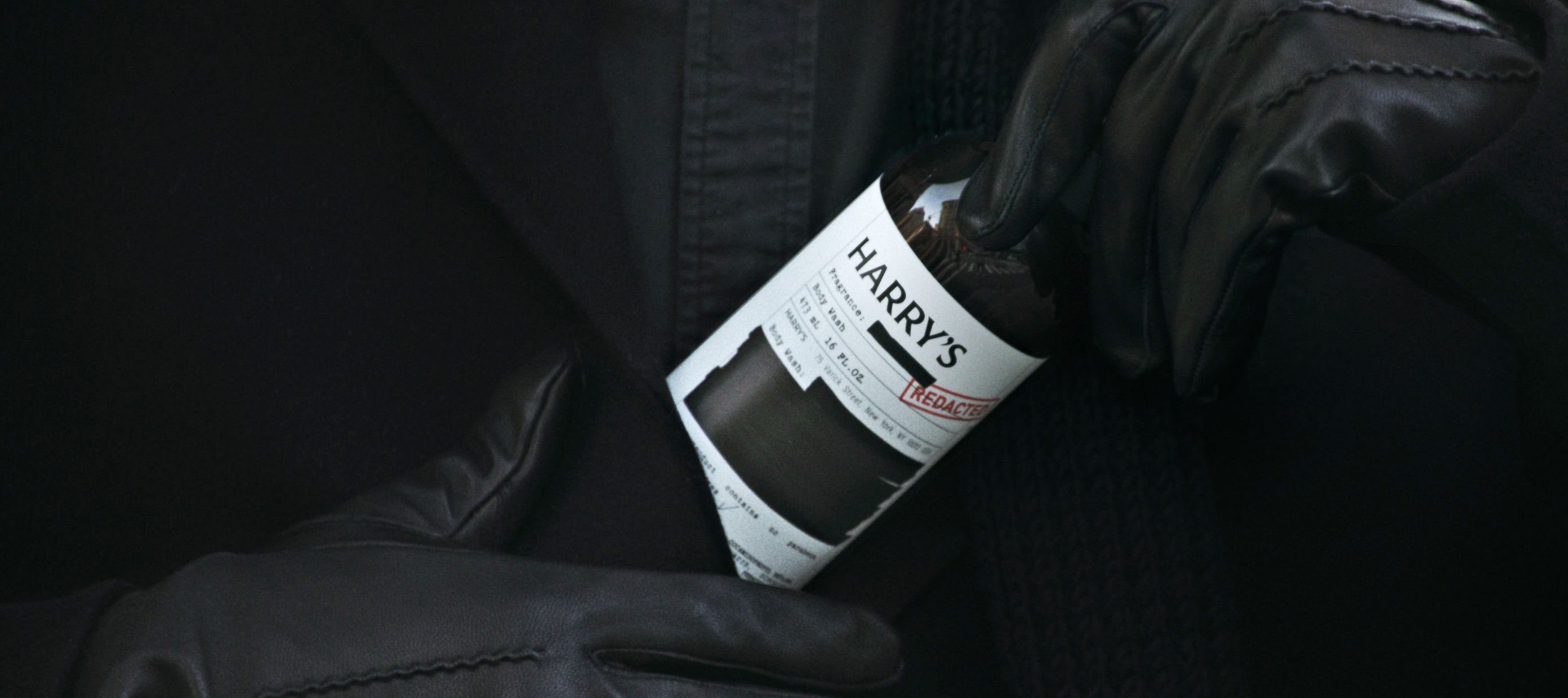 Black gloves holding Harry's redacted Body Wash bottle