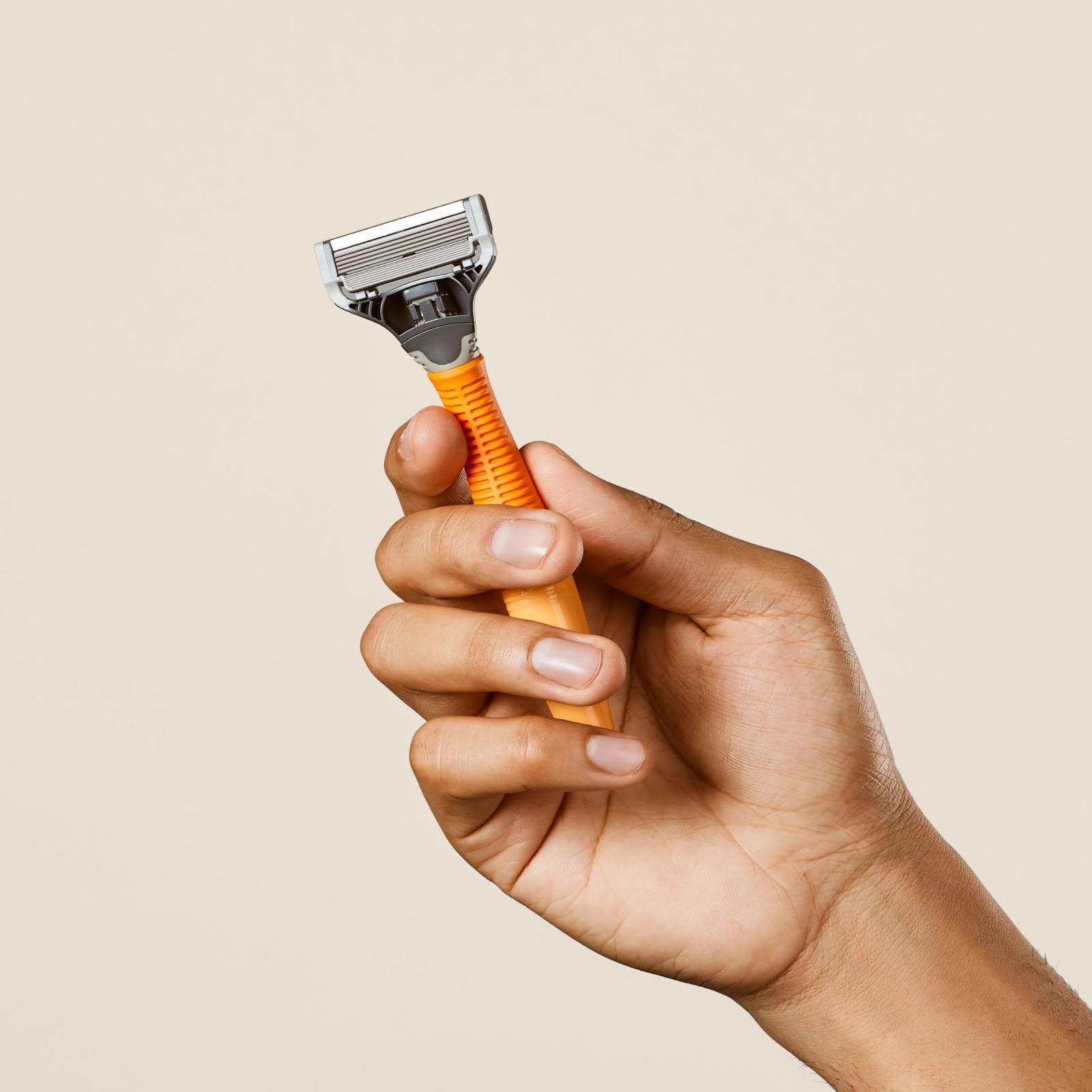 Hand holding the Truman Razor in the color Ember.
