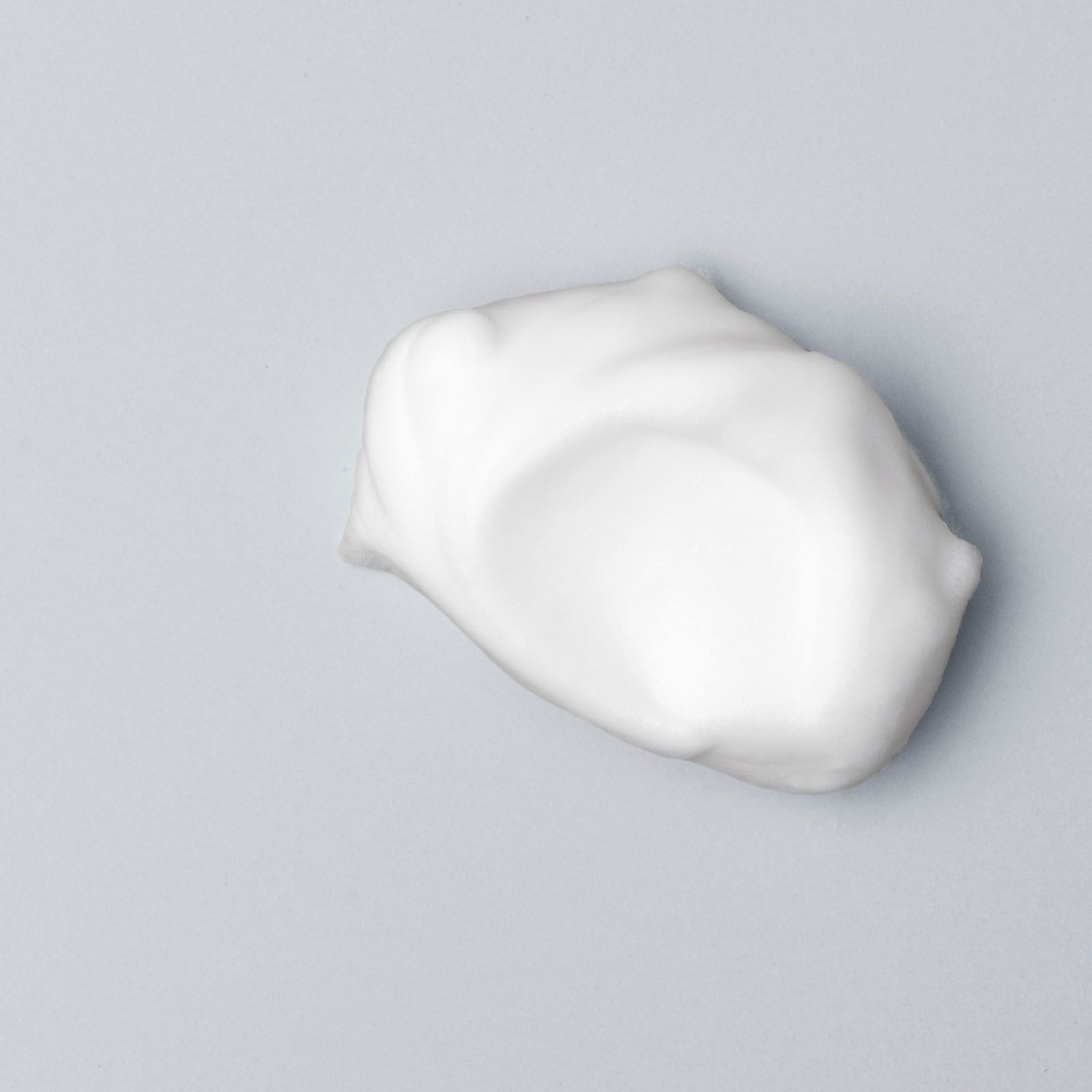 Pillowy white dollop of the Shave Gel on a grey background.