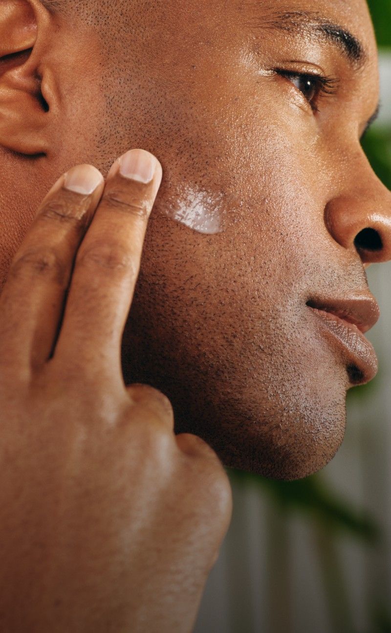 Man applying cream to his face with a blurred background.
