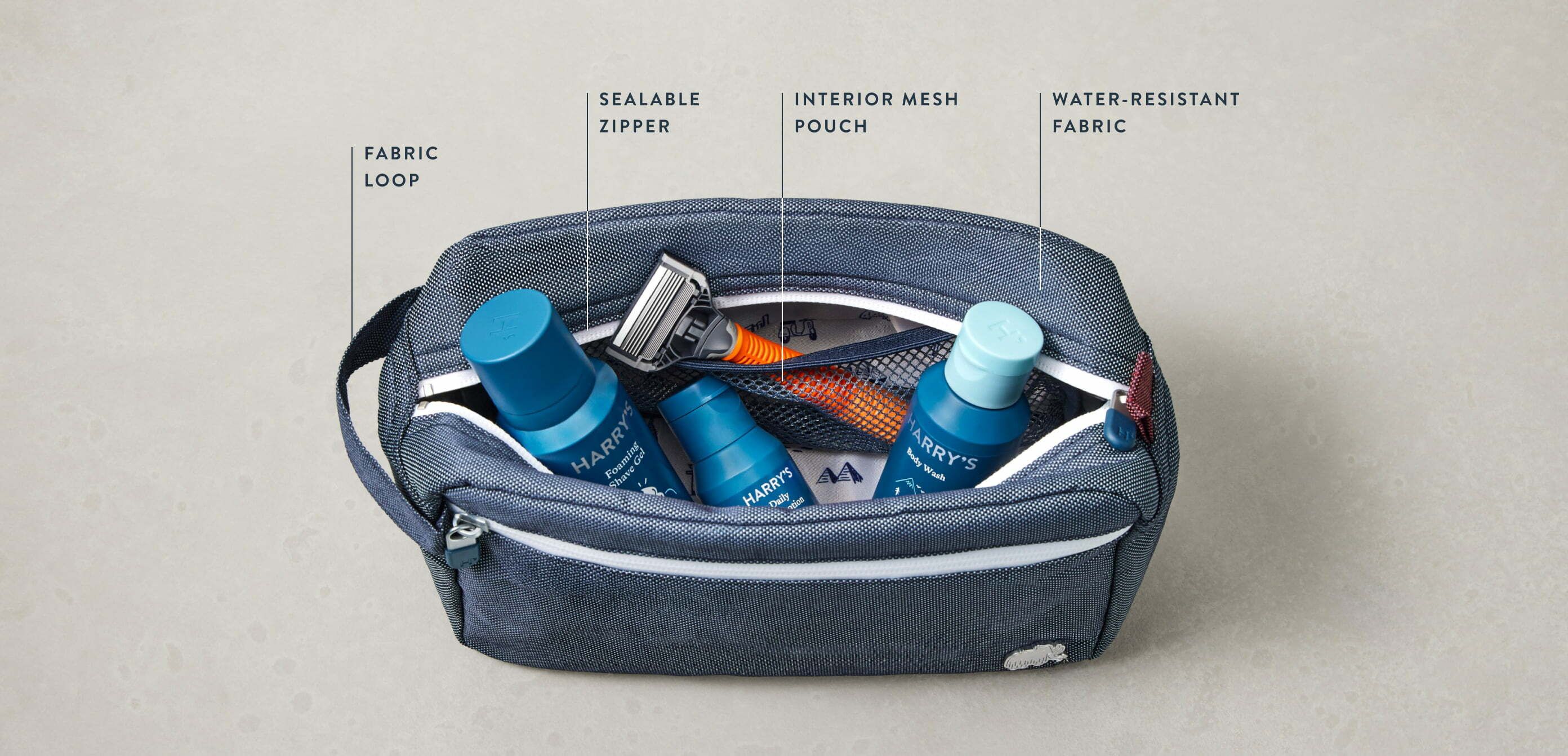 Toiletry bag unzipped to show Truman razor and travel sized products inside.