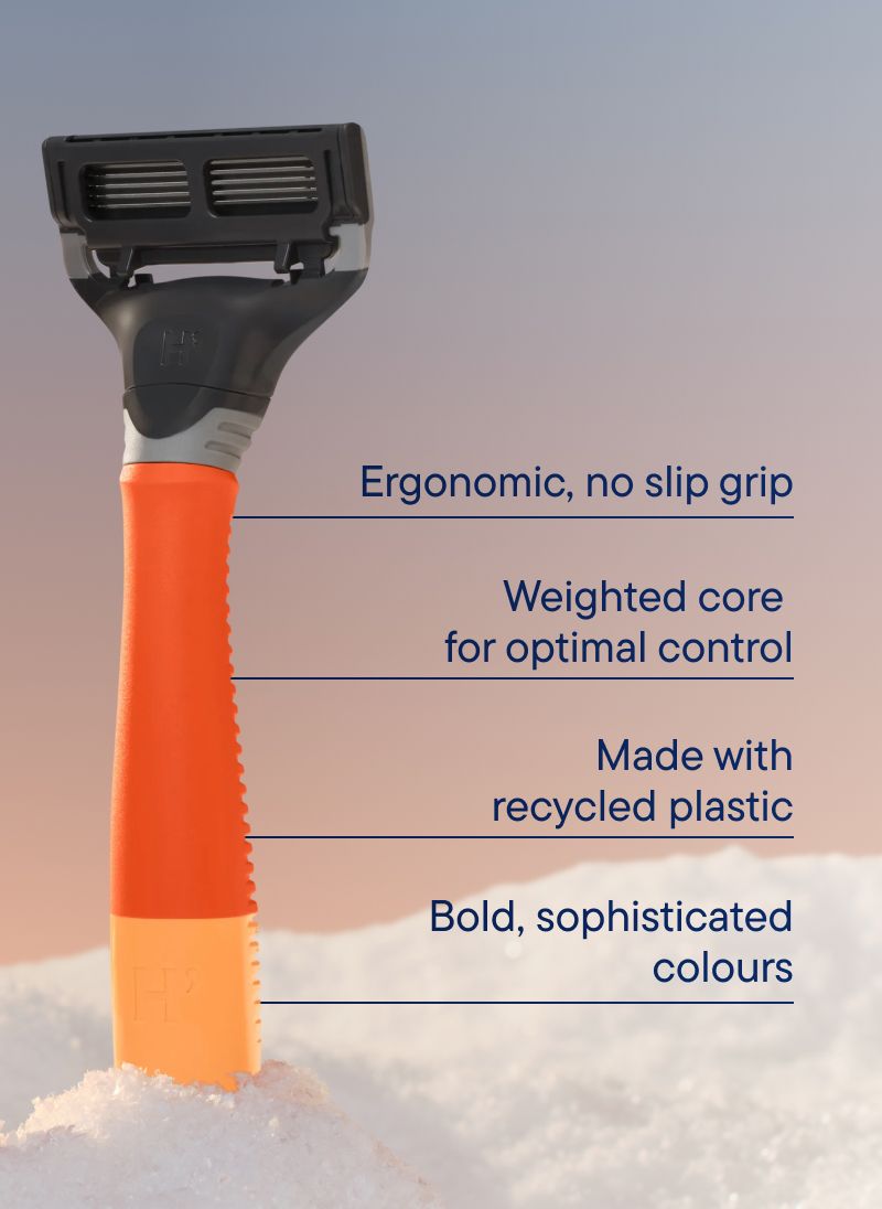 An orange handled razor in a bank of snow