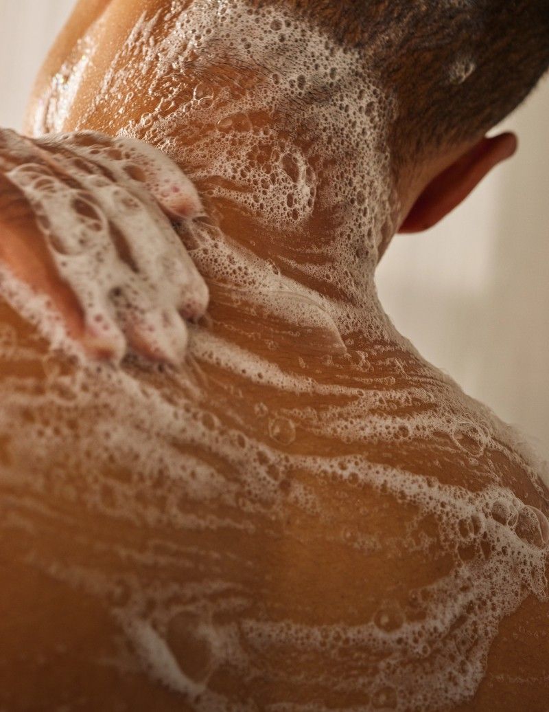 Close-up of a person's neck with soap suds.