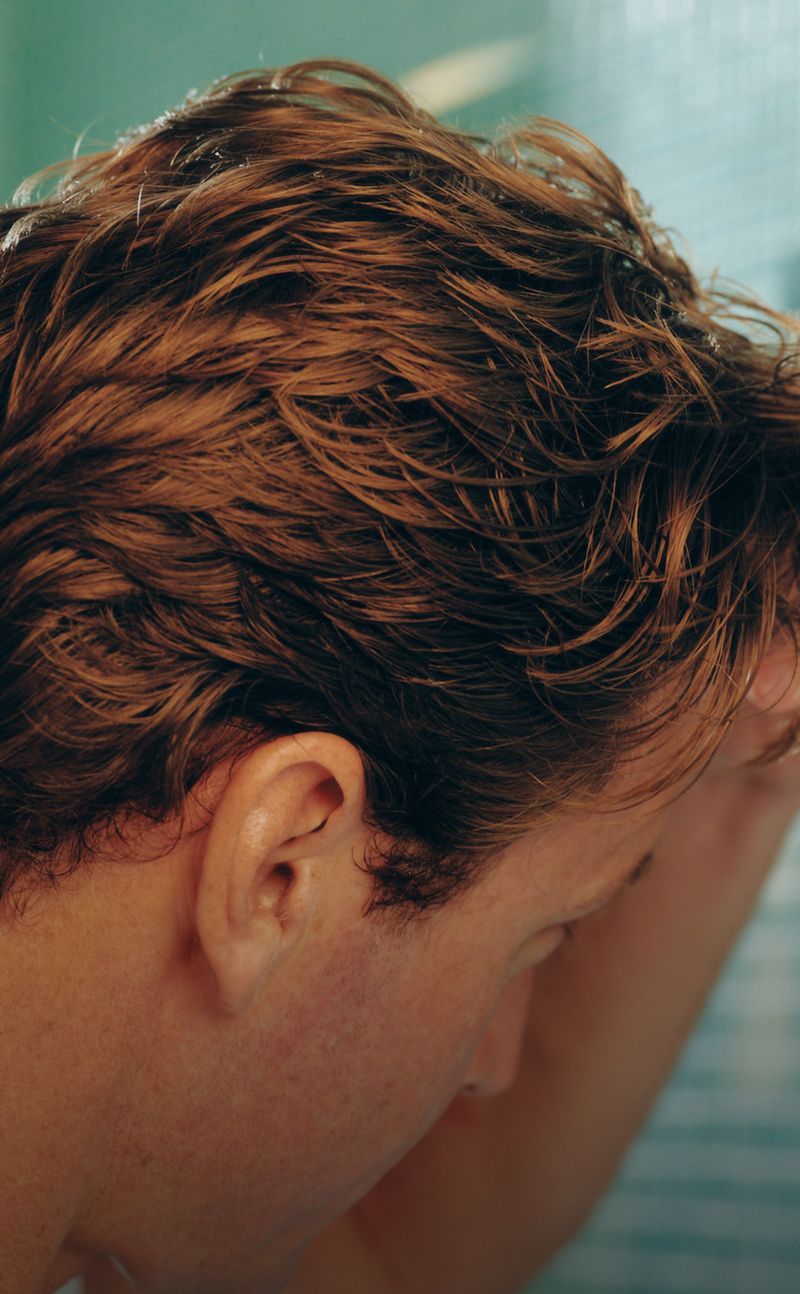 Person applying product to hair in a bathroom setting