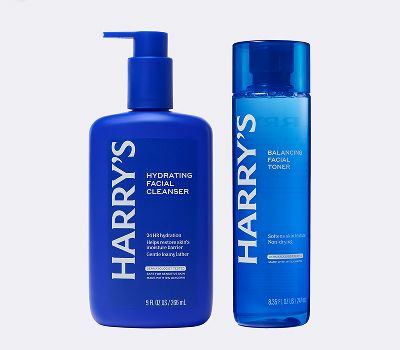 Blue bottles of face care products that have white next on them against a grey background