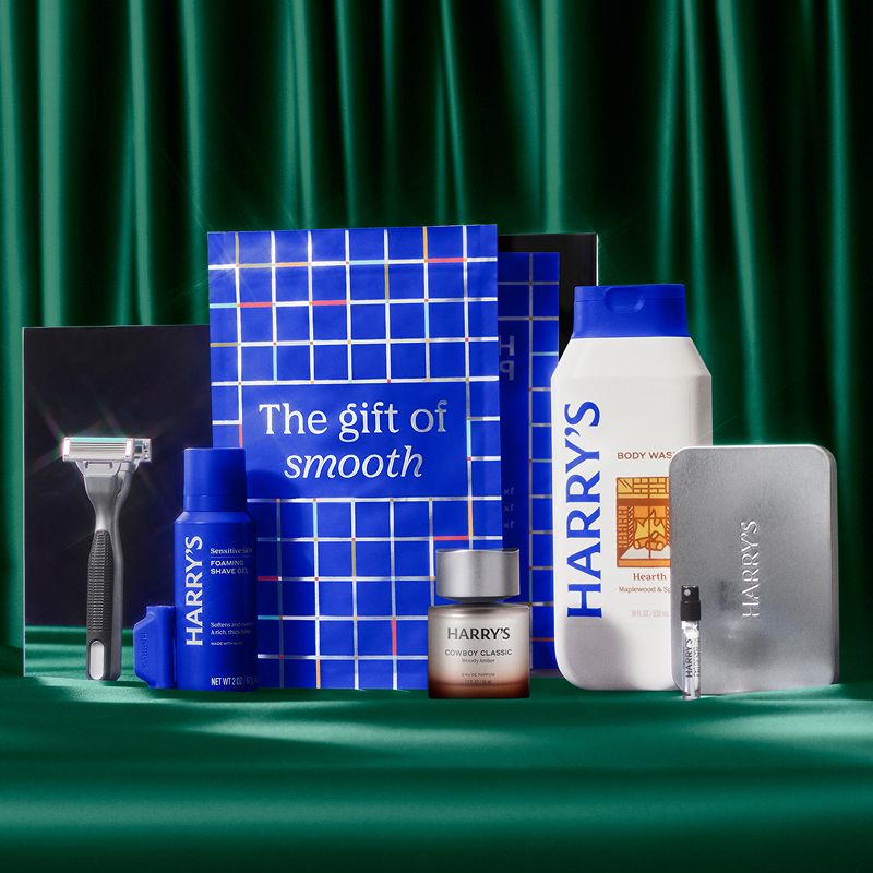 Harry's Plus Handle, Shave Gel, Cologne and Body Wash next to a blue bag that reads "the gift of smooth" on a green background