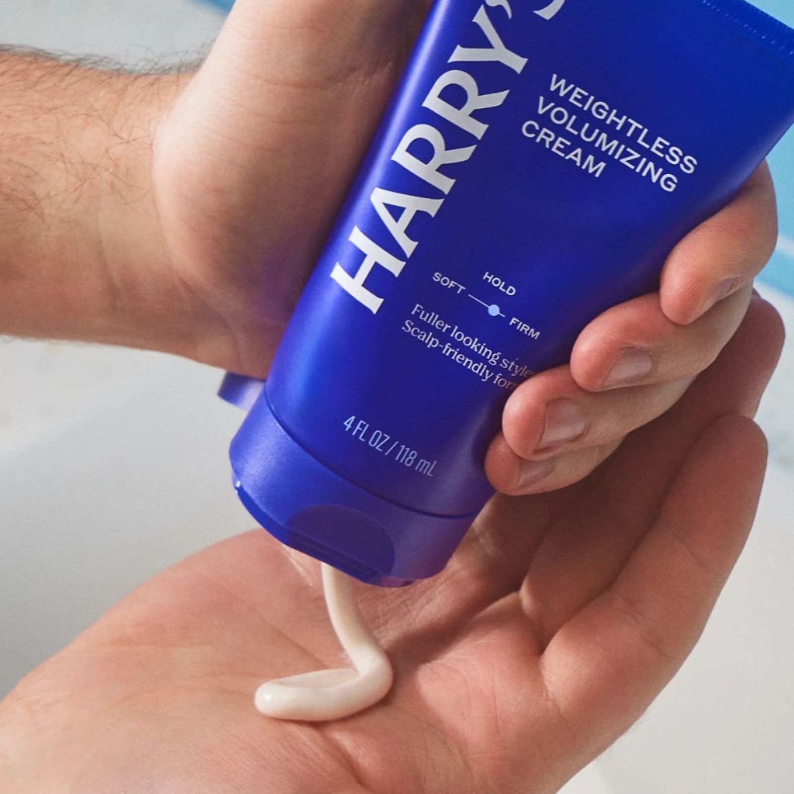 Tube of Weightless Volumizing Cream being squeezed to release product onto a hand.