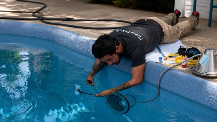 Homeowner inspecting a low pool with a surface crack at a Bennett, Colorado backyard pool