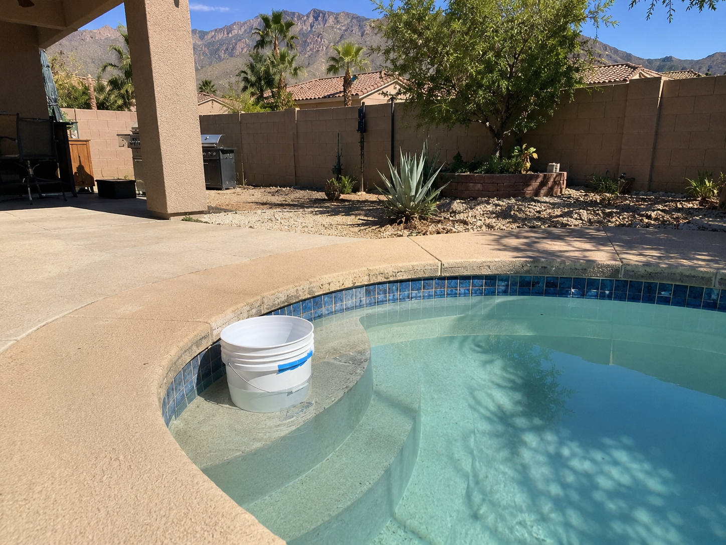 Centennial Hills Las Vegas backyard pool with a low water line and a bucket test on the top step, dry desert mountains behind.