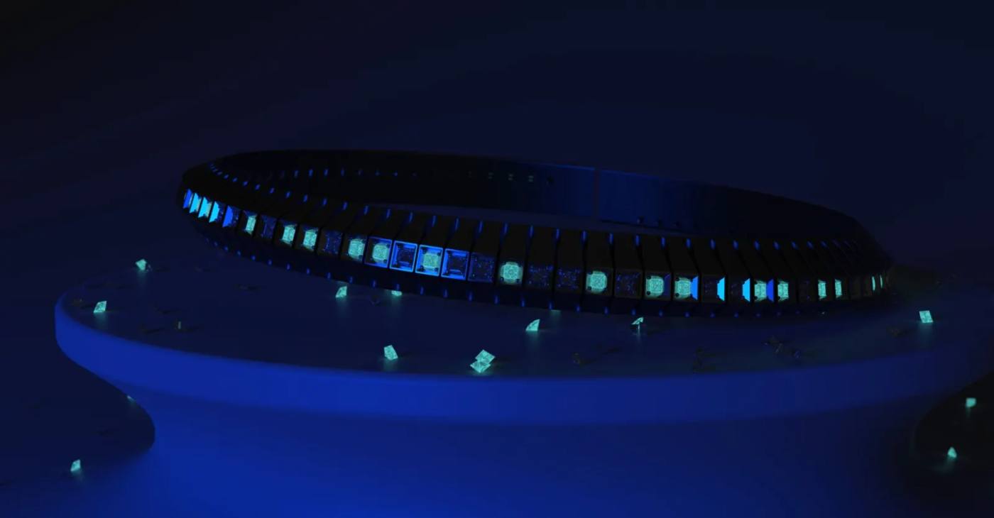 Bracciale SEGNO in titanio su un piedistallo, illuminato a luce nera: i diamanti taglio princess brillano di azzurro nel buio.