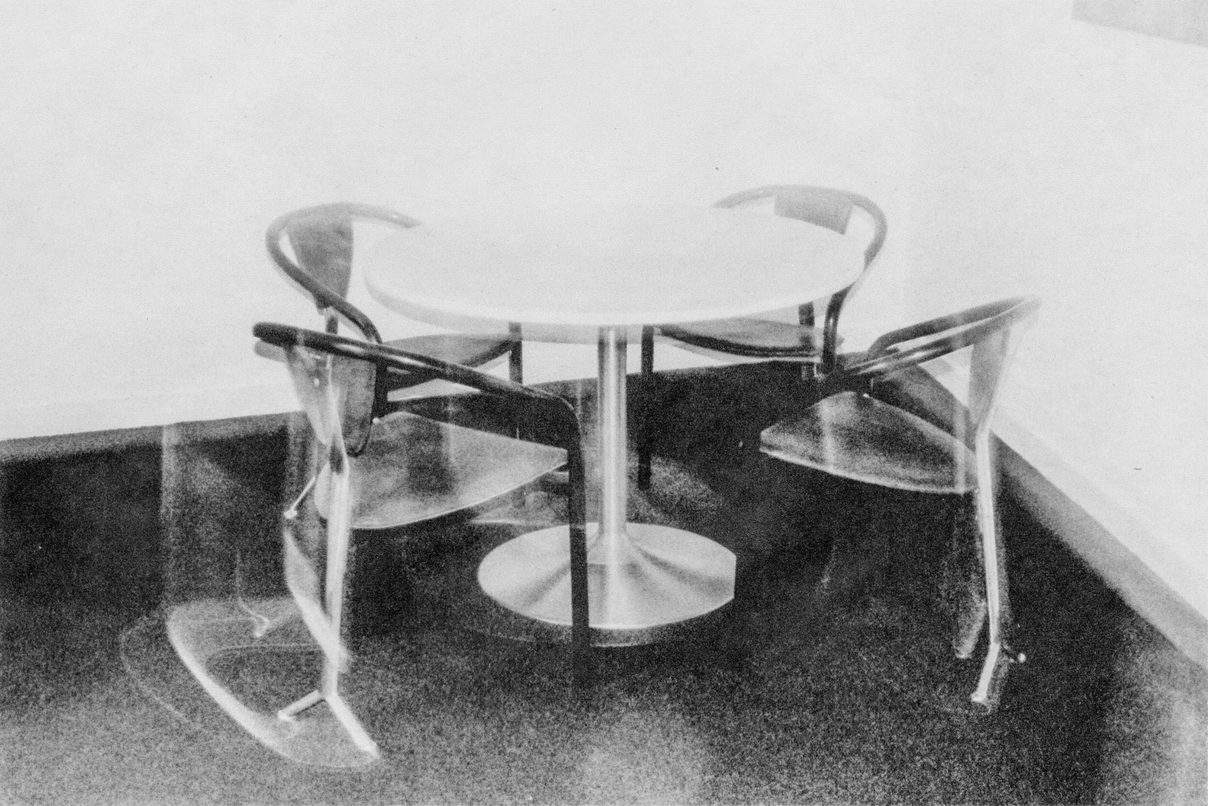 black and white image of a table with four chairs