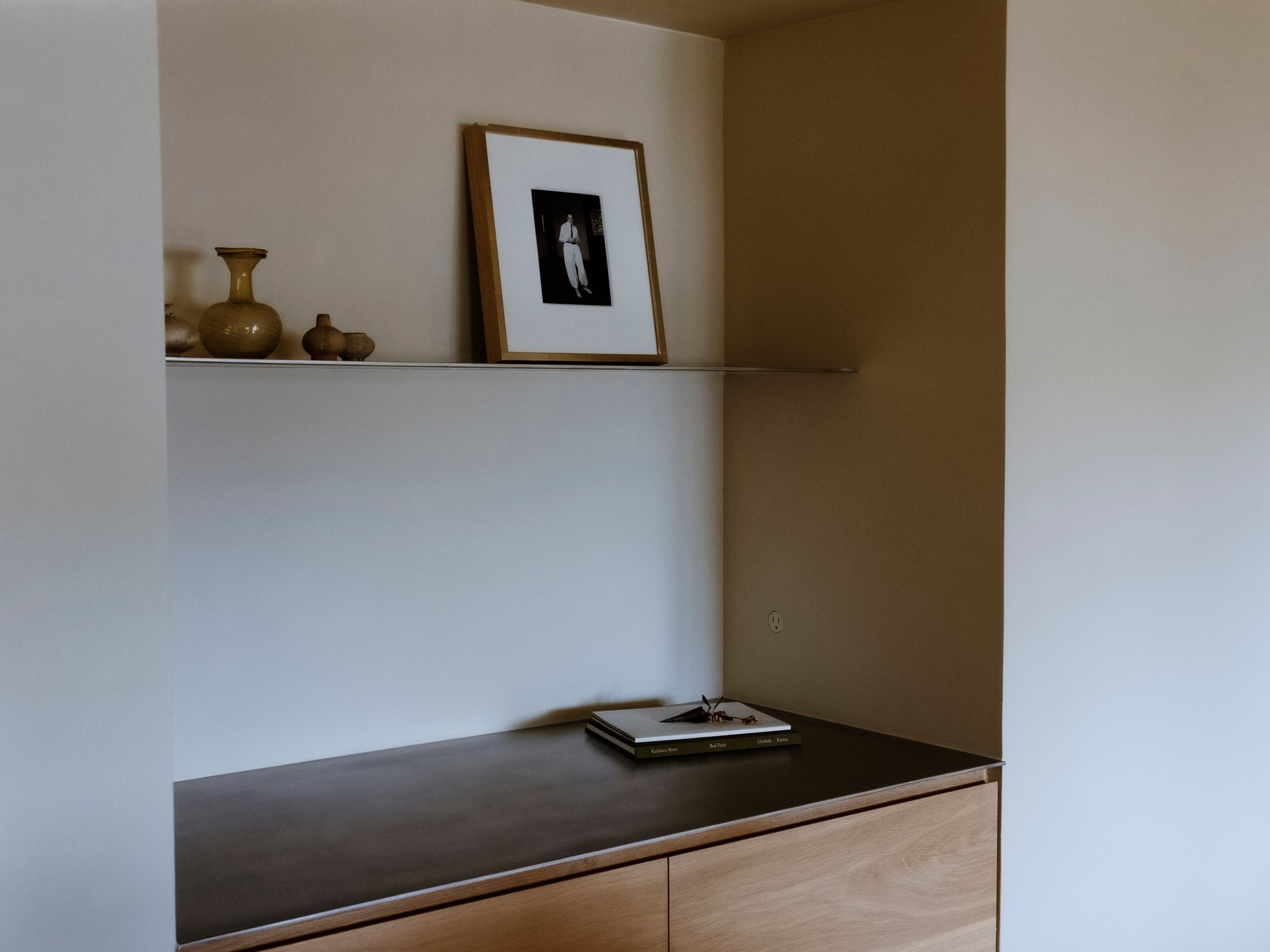 a stainless steel countertop with wooden cabinetry, a shelf with August Sander photograph on it, woe, width over ears