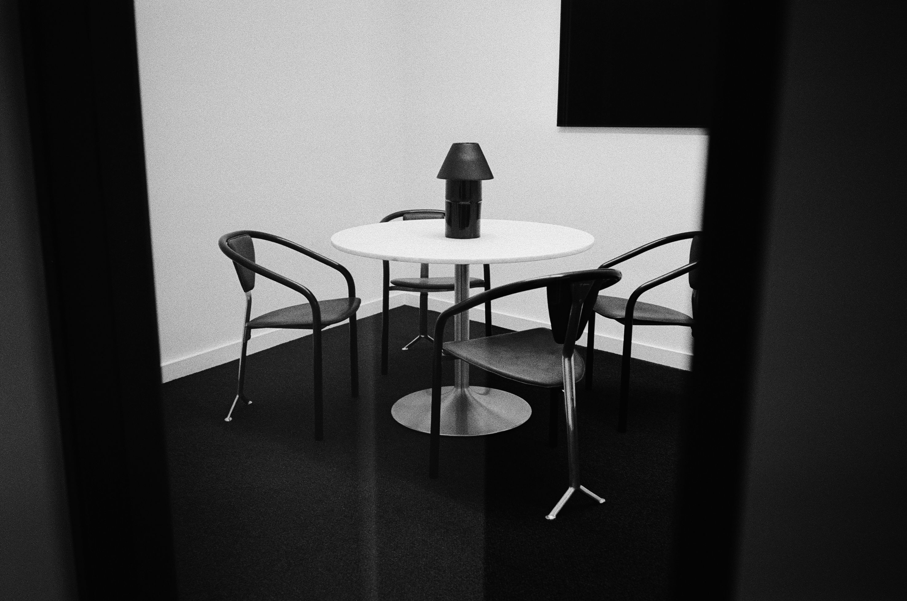 a black and white image of an office work room with a round table and set of chairs
