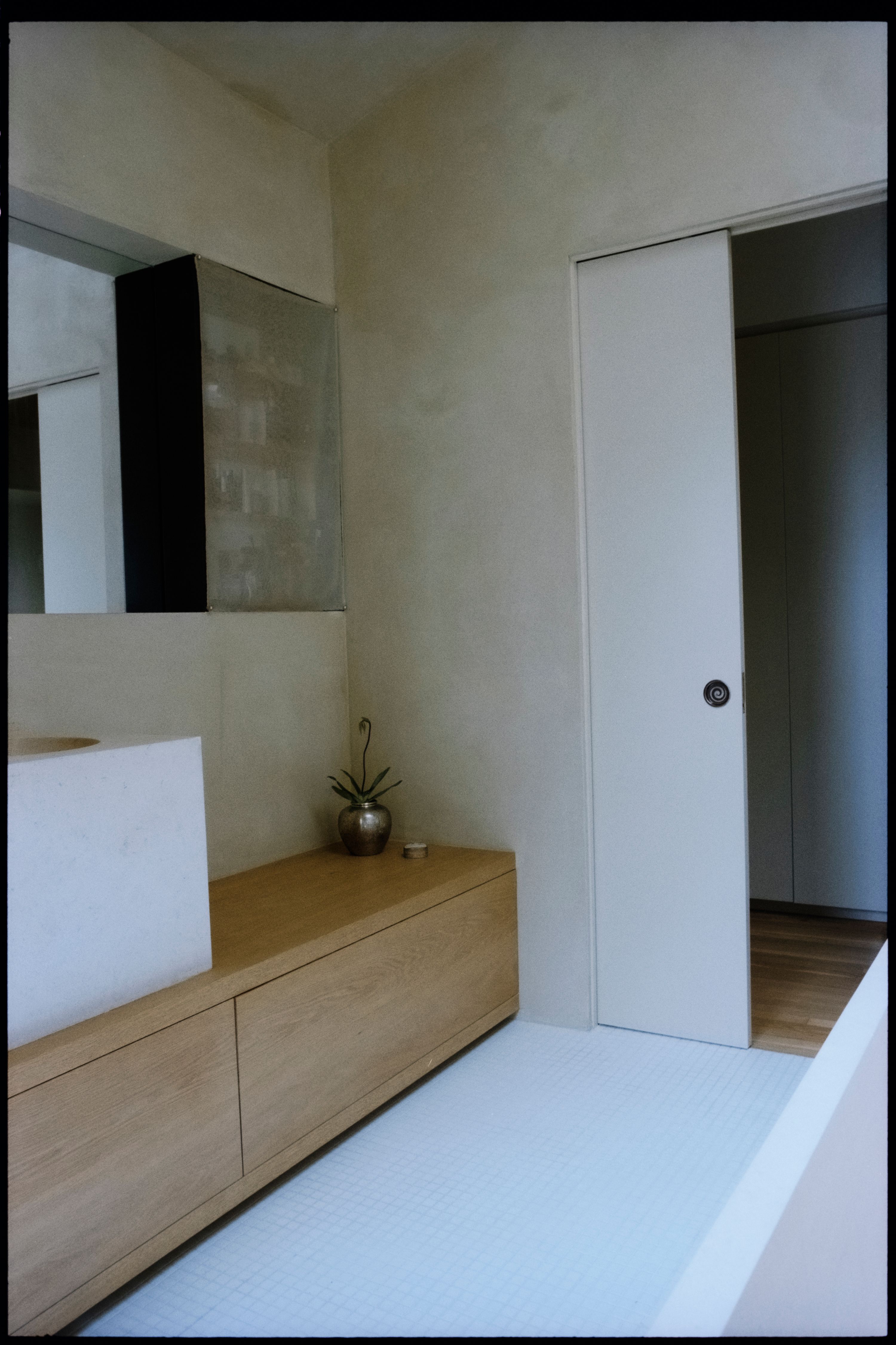 a room with white tile floor, oak cabinetry, and pocket door with inset pull, WOE, Width Over Ears