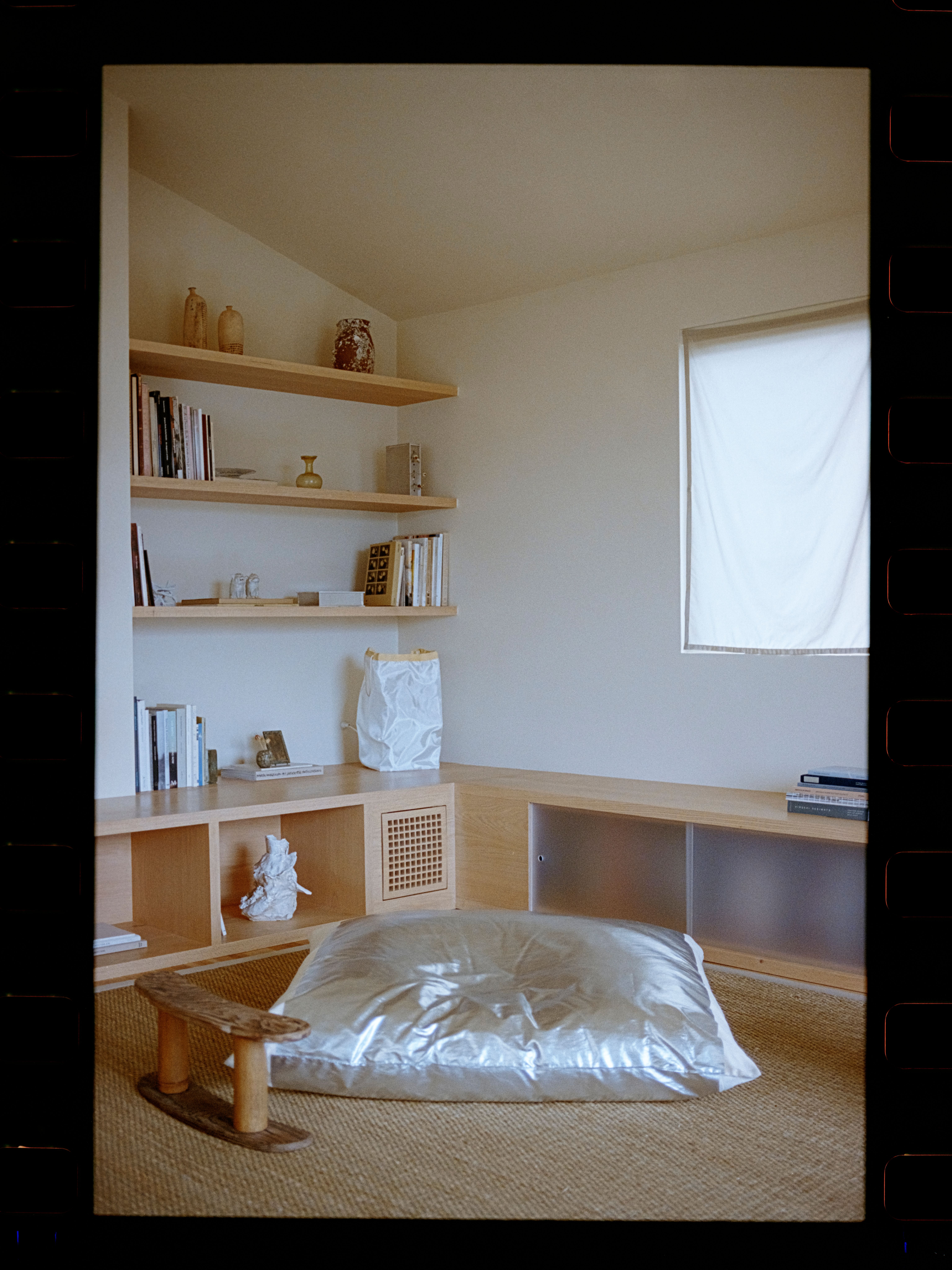 a large silver pillow on a seagrass rug with a bookshelf in the background, WOE, Width Over Ears