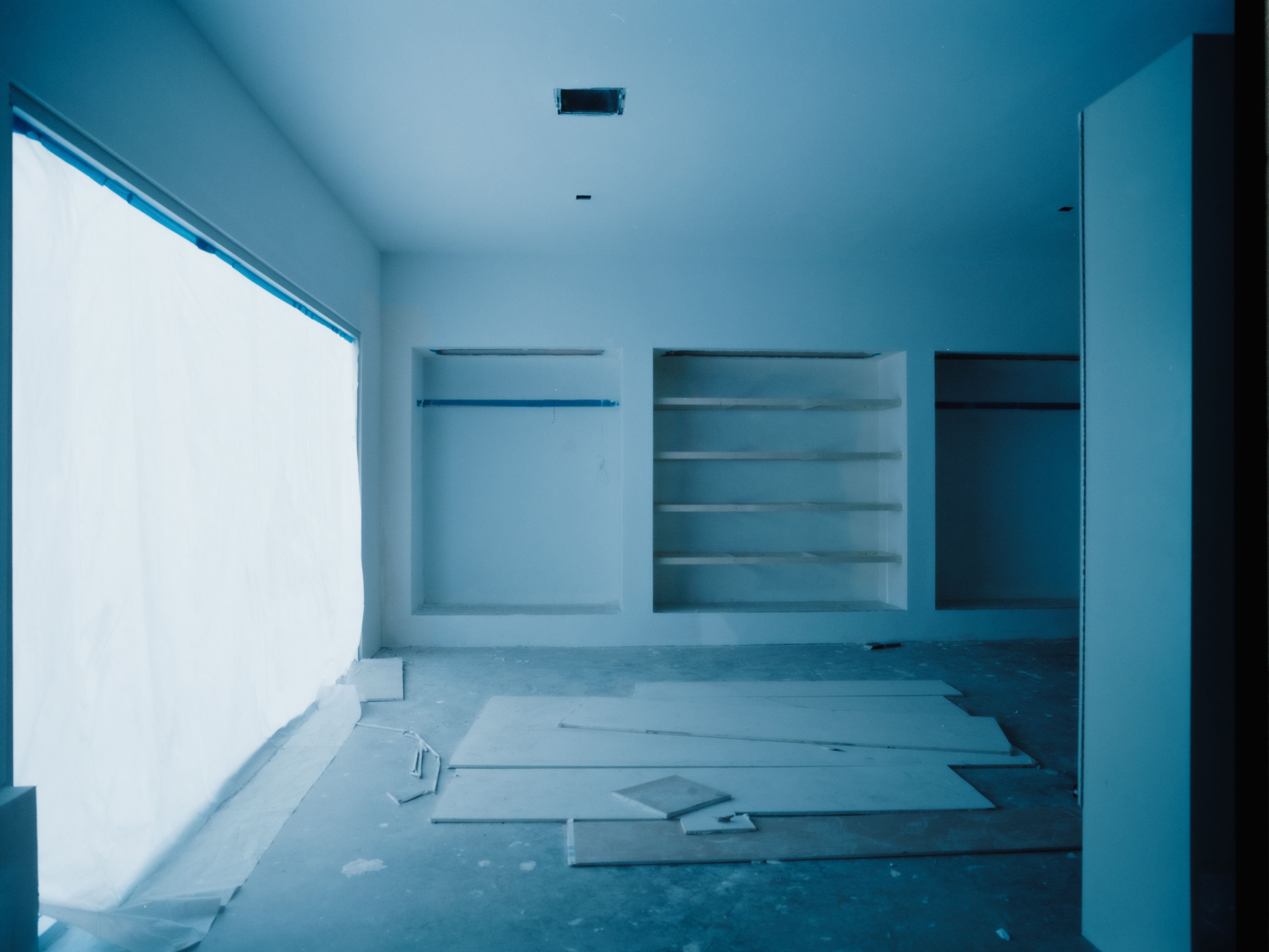 a large window within a large room with a blue hue and niches with shelves, WOE, Width Over Ears