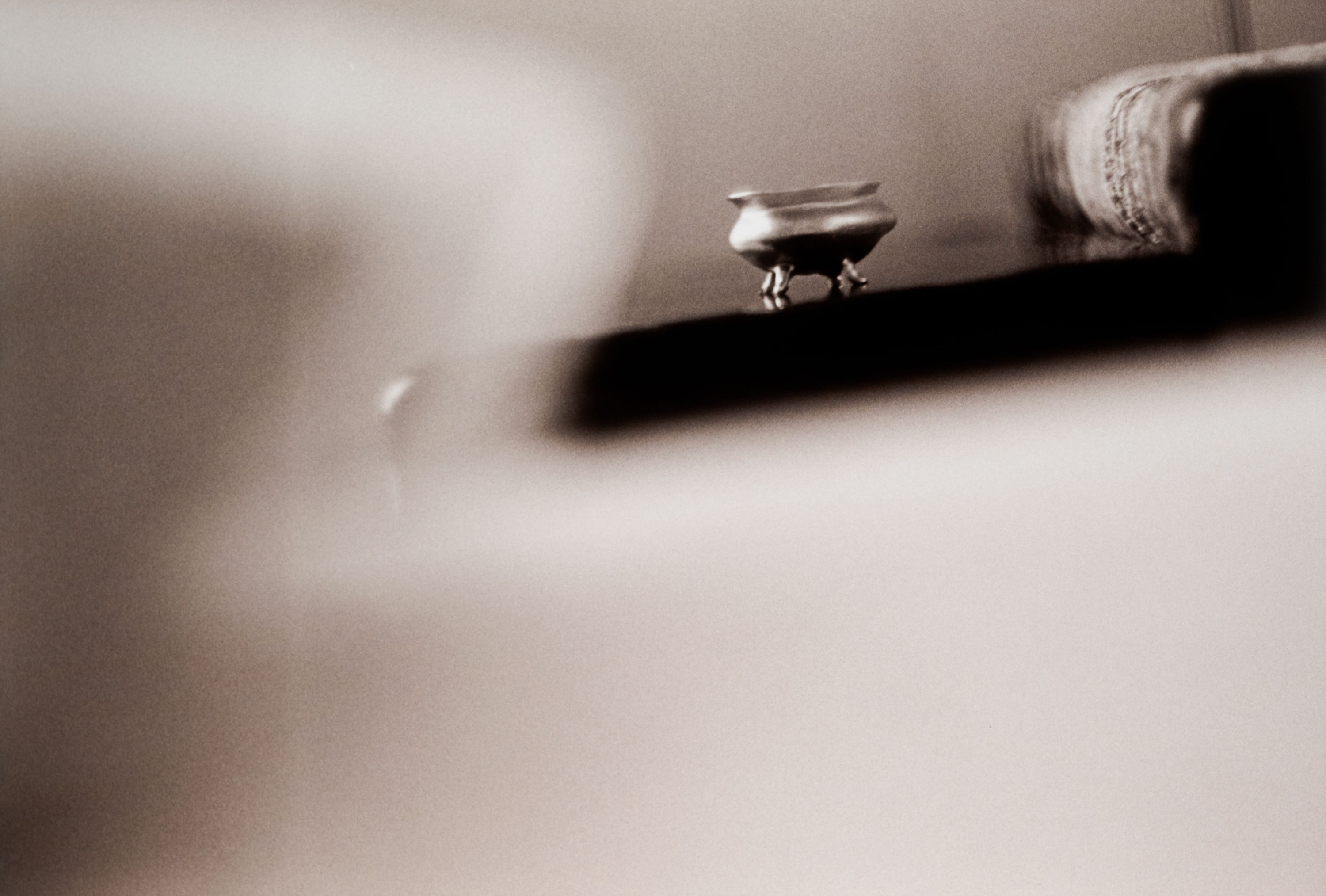 a black and white image of a small glass vessel on a black table