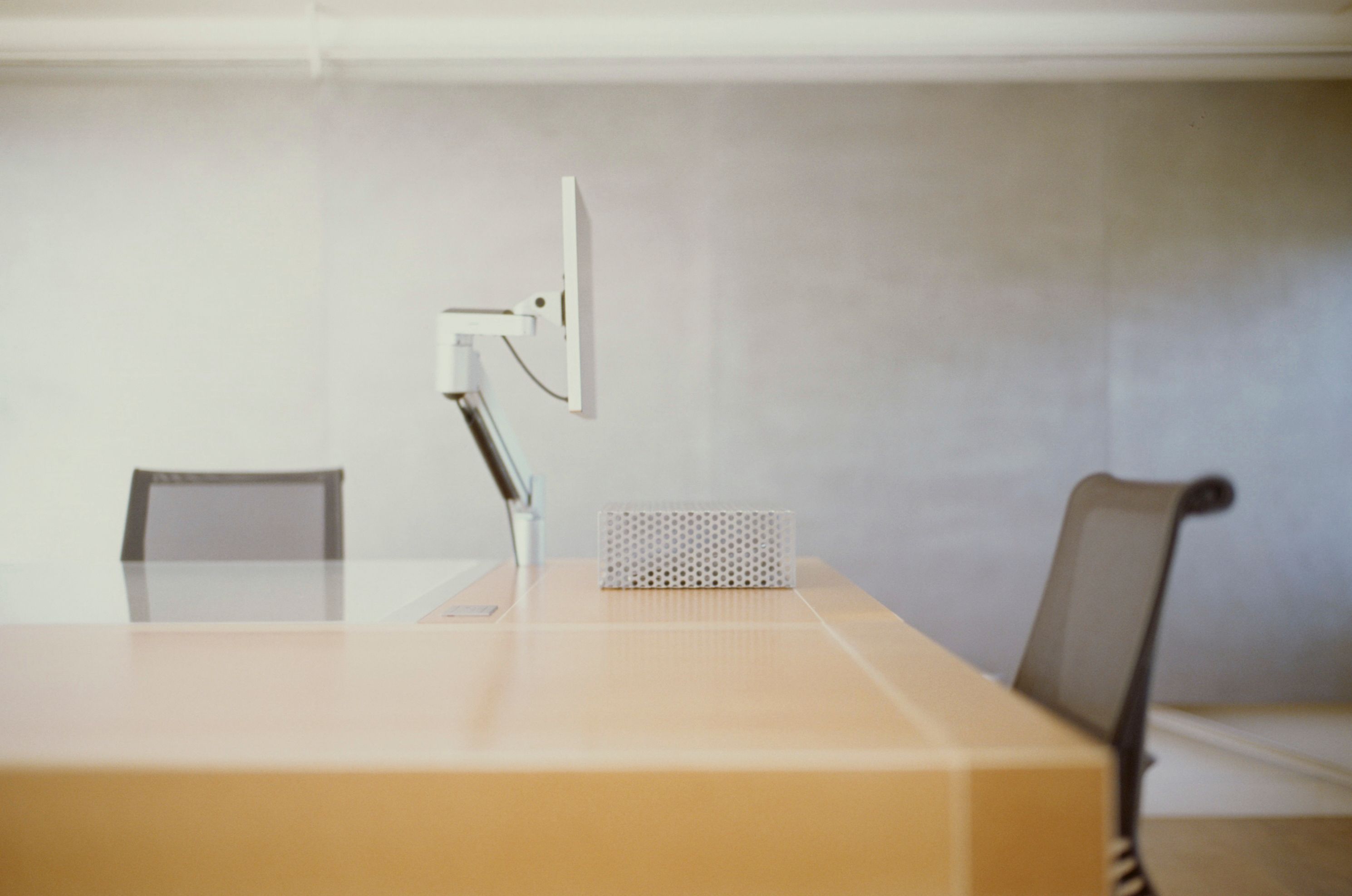 a work desk with an adjustable arm computer screen and desk chairs