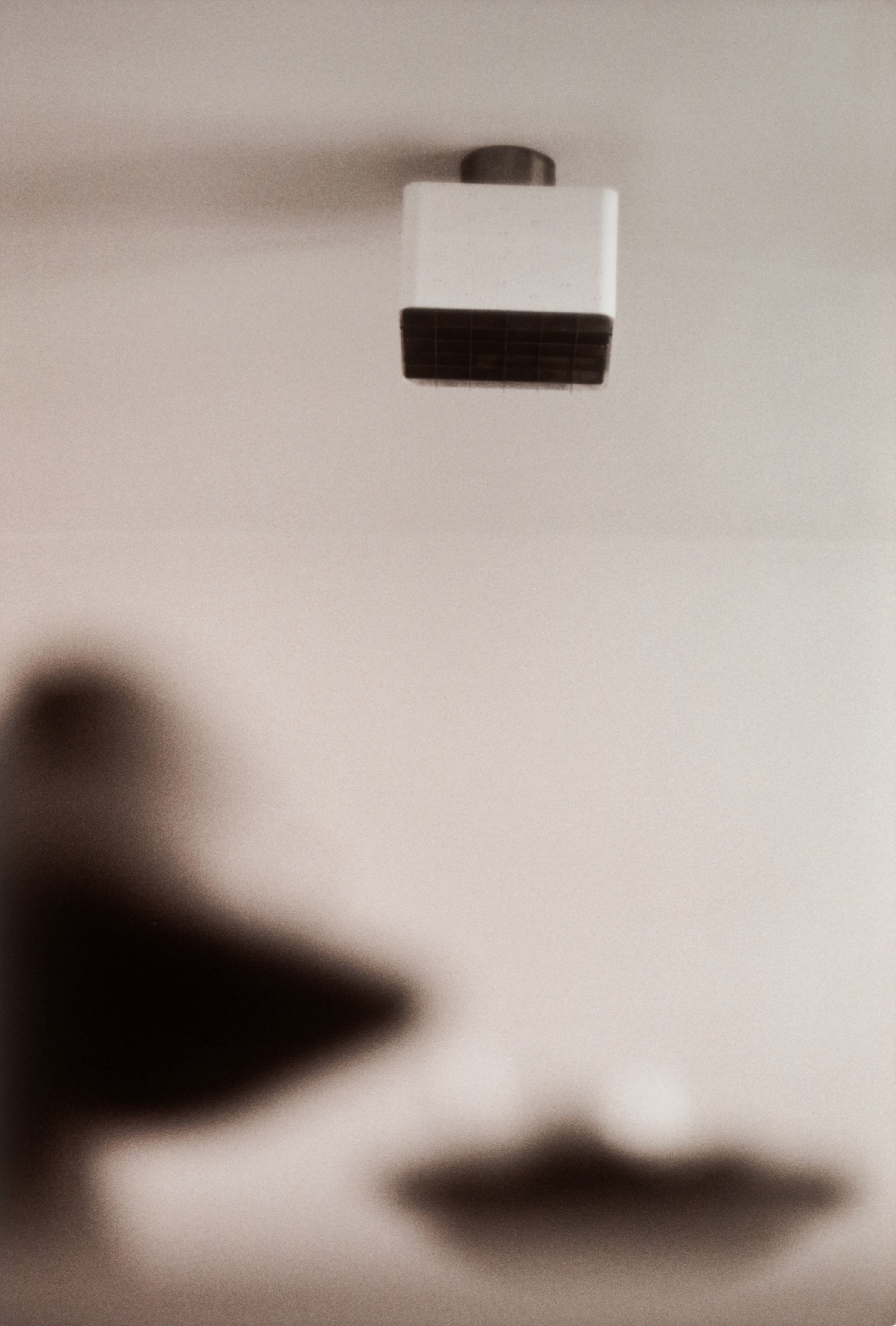 a black and white image of a light fixture against the ceiling