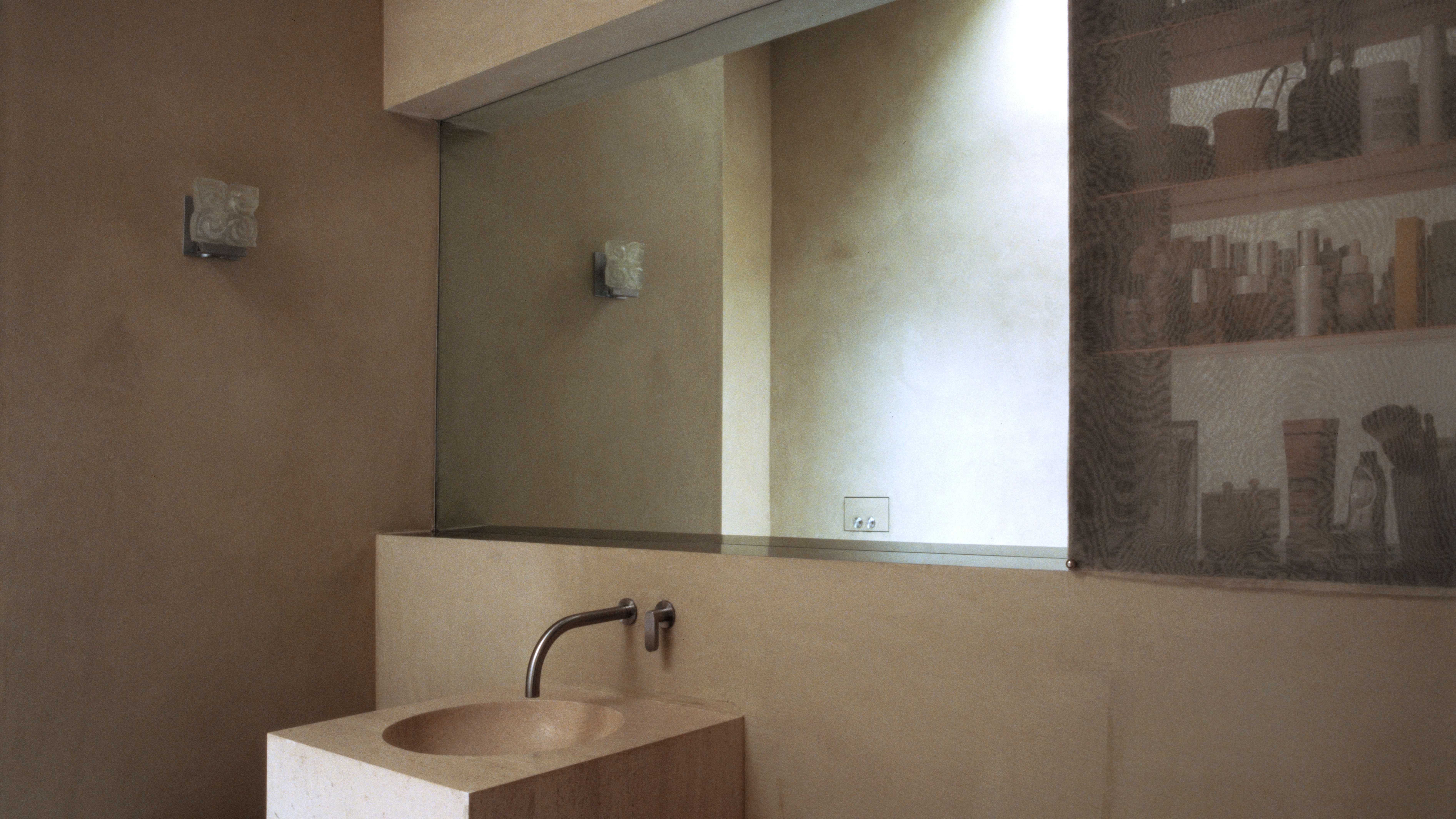 a long mirror with a faucet underneath, over a round sink in a square piece of stone, WOE, Natalie Weinberger