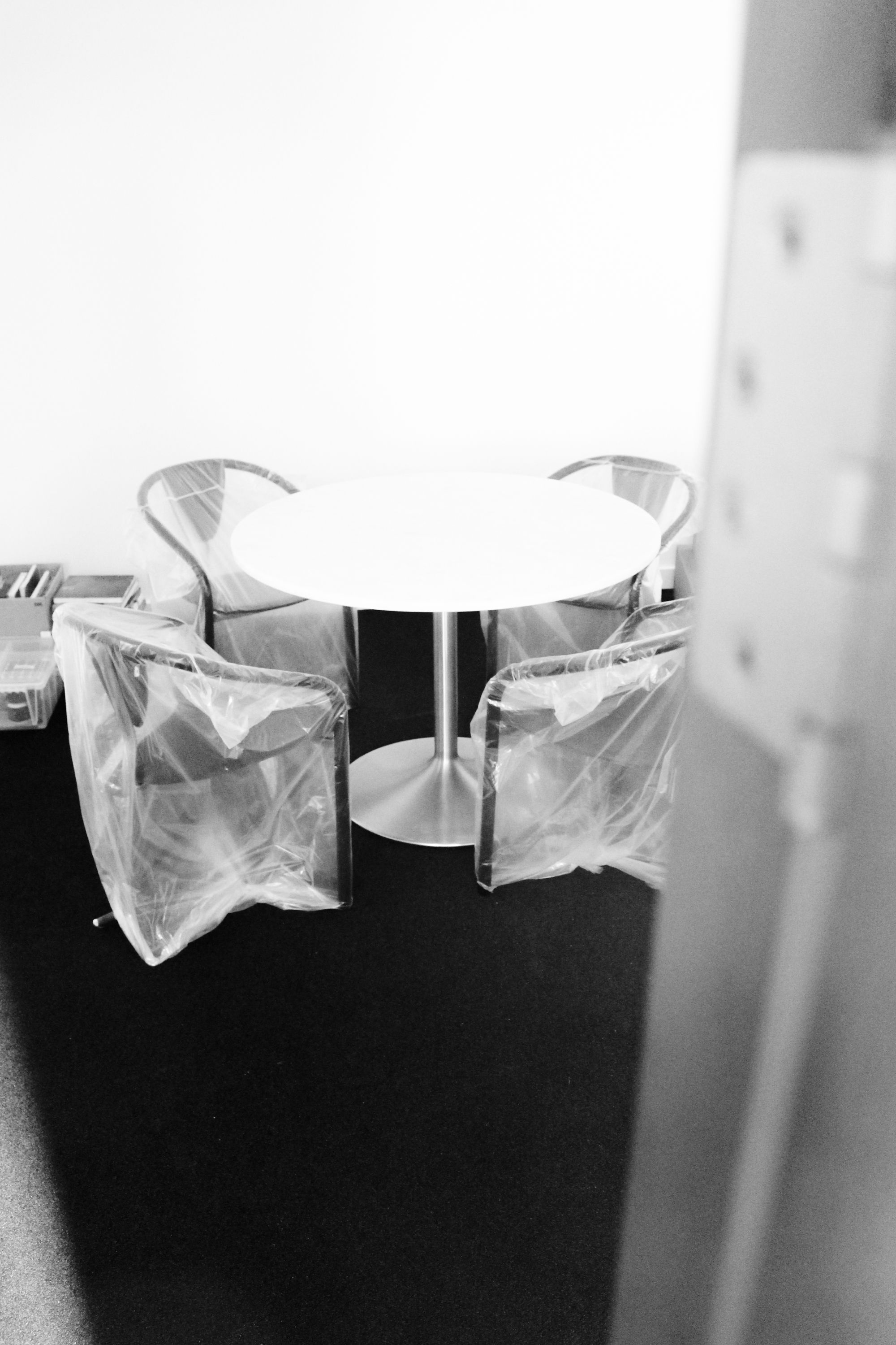 a round table with white stone top and metal base, with four chairs around it, covered in plastic