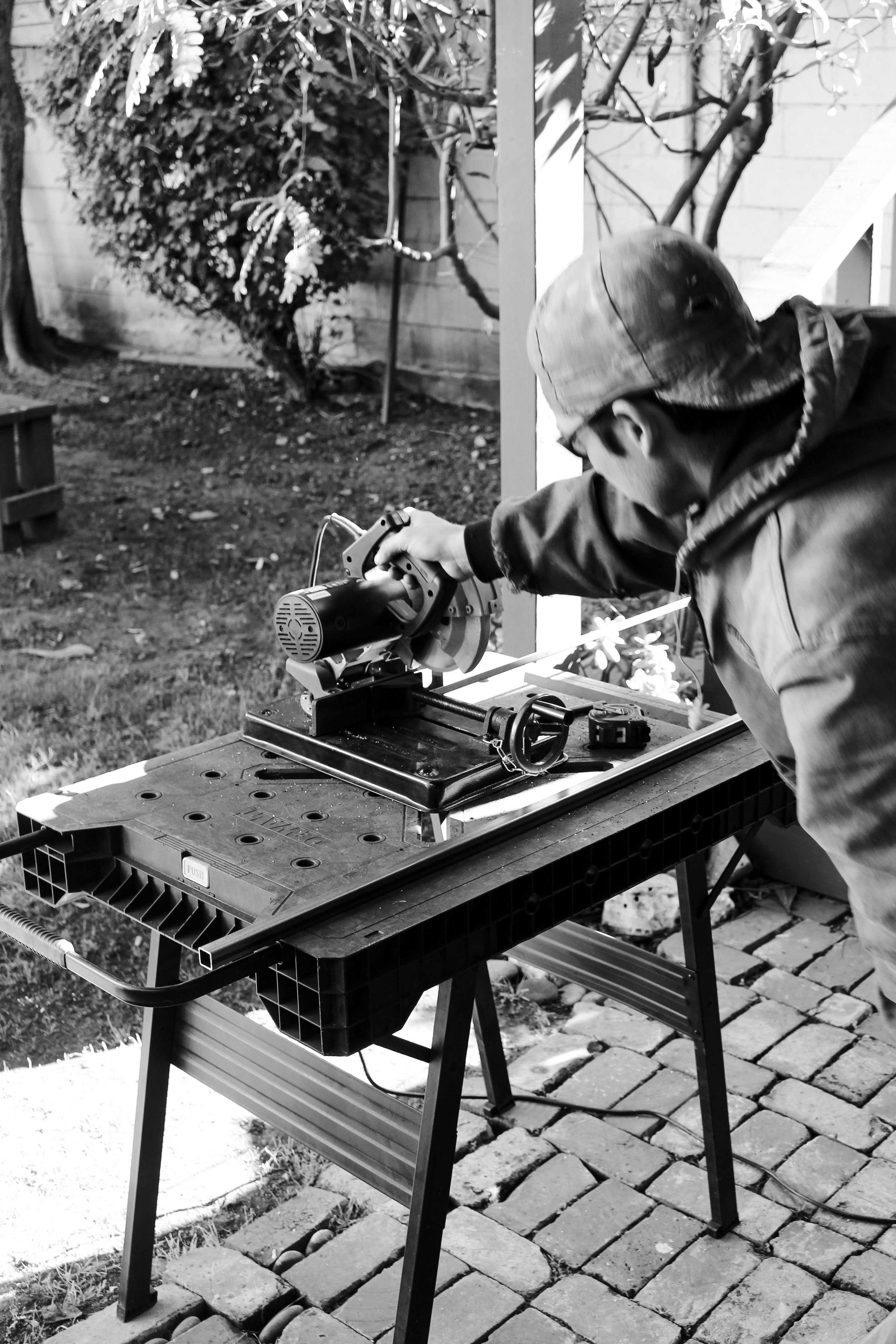 a black and white image of a person cutting a piece of metal with a saw, WOE, Width Over Ears