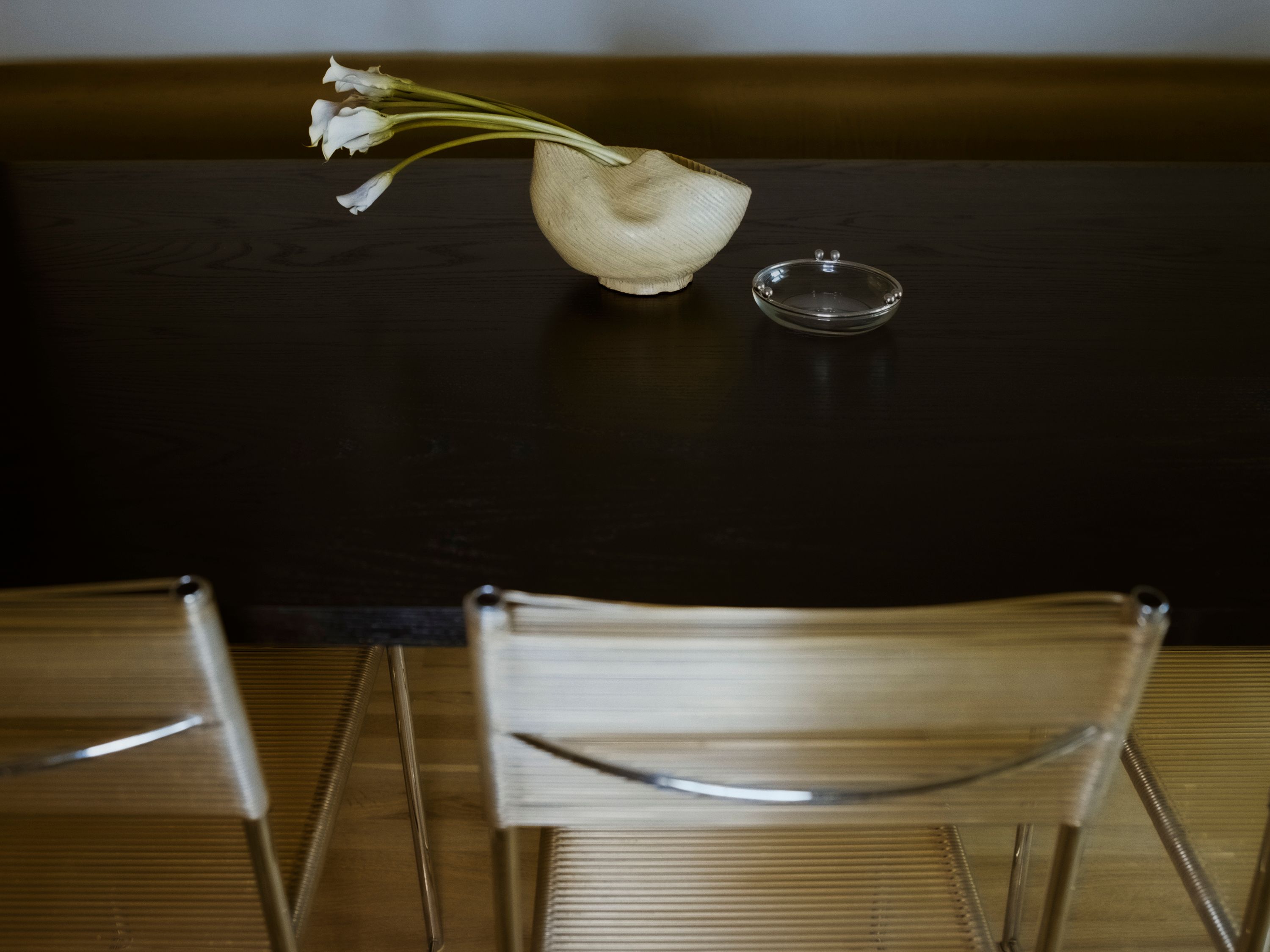 a bowl sitting on a black table with a yellow chair in the foreground, WOE, Width Over Ears, Design
