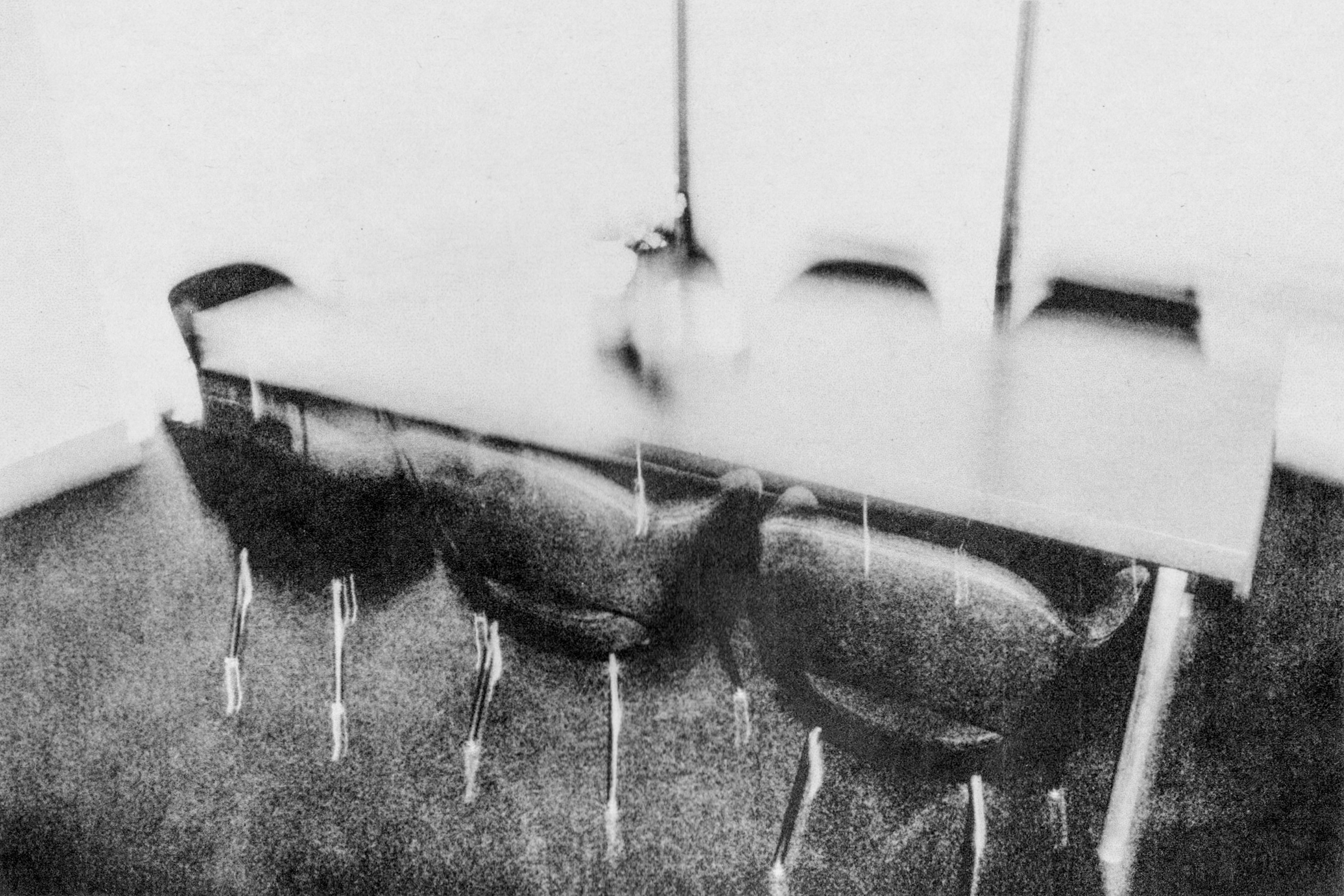a blurry black and white image of a room with a long table and set of black chairs
