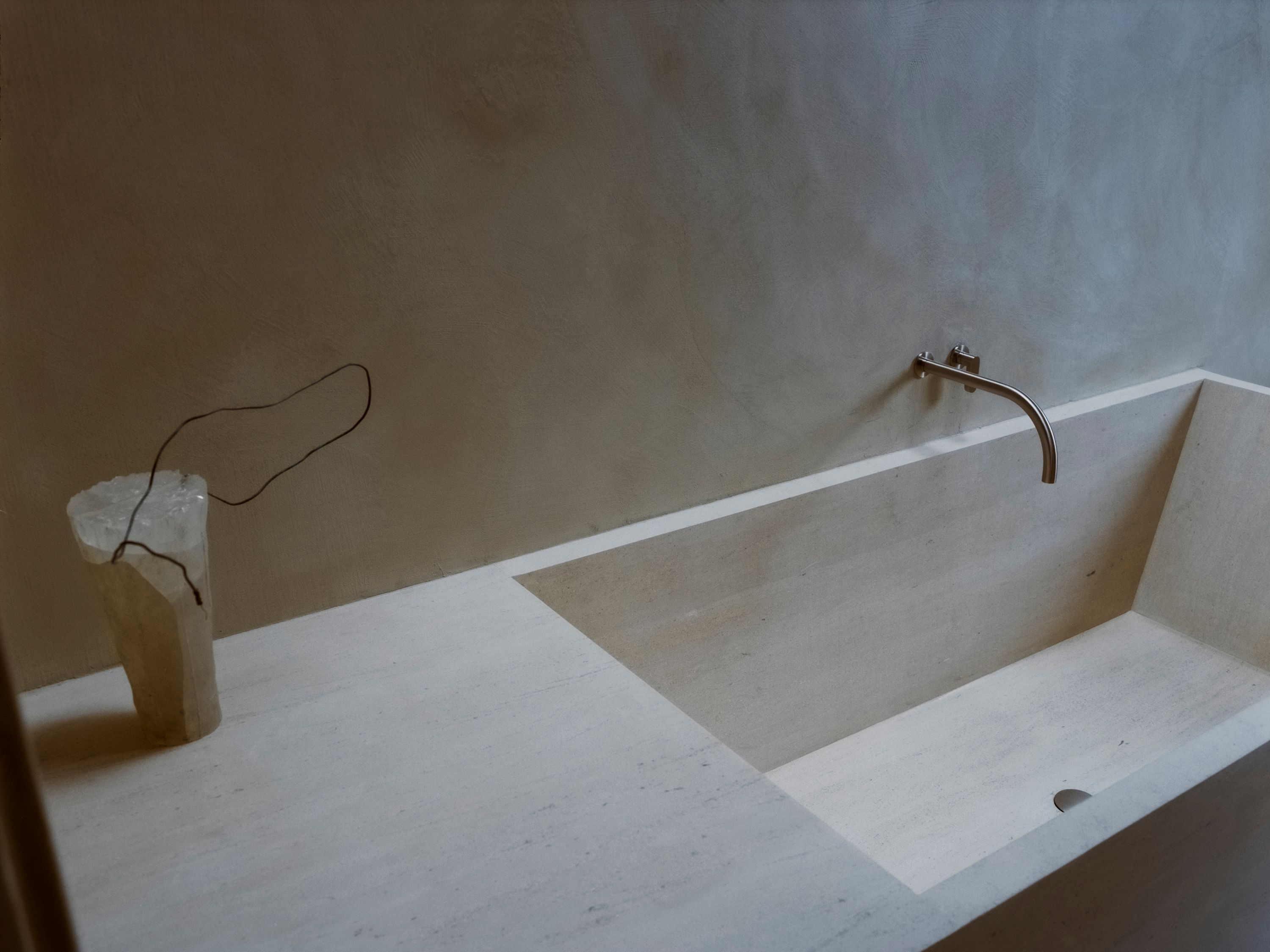 a stone bath tub with silver plumbing and textured wall, WOE, Width Over Ears