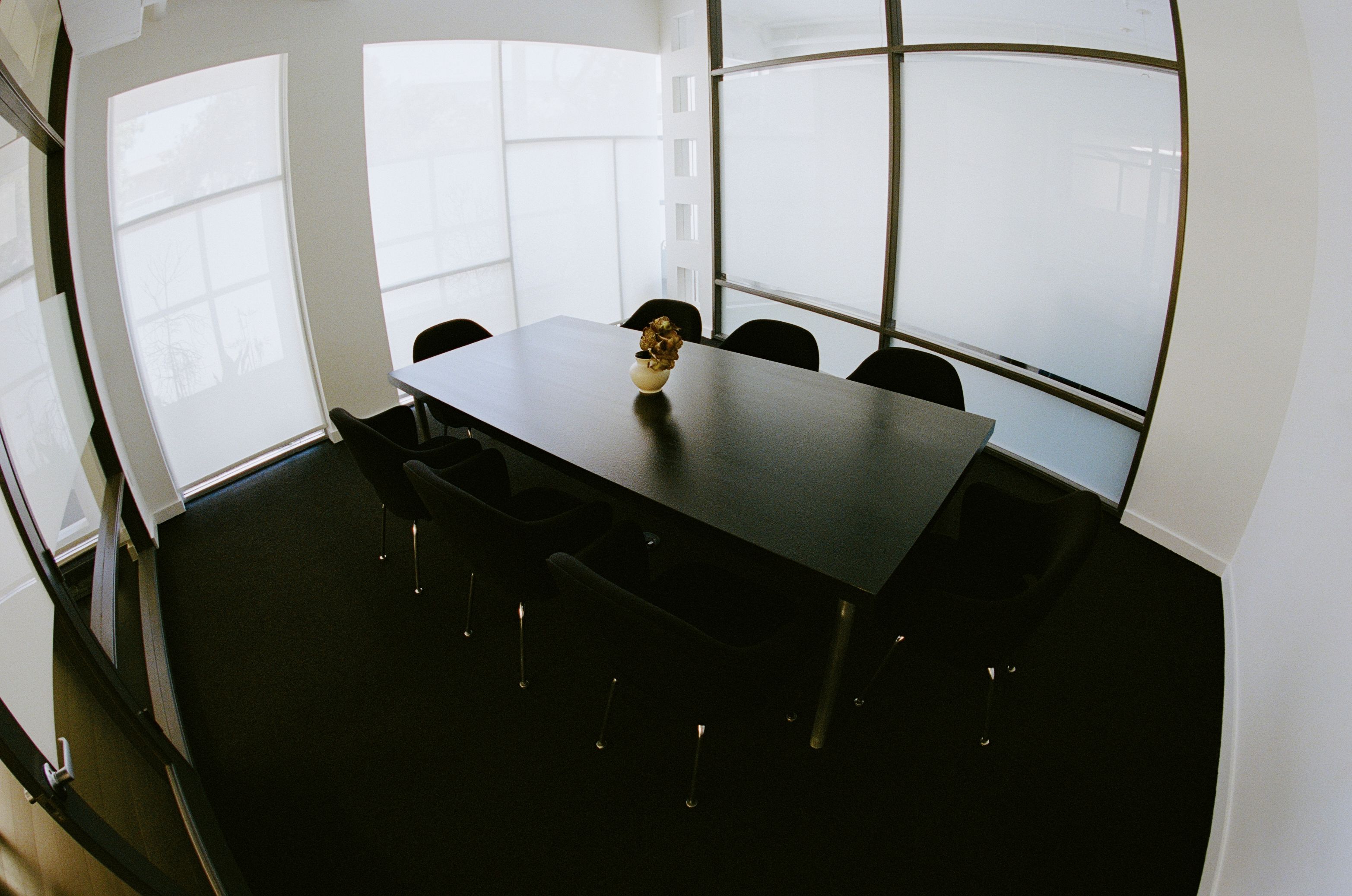 a conference room with black conference table and chairs, and an orchid flower arrangement