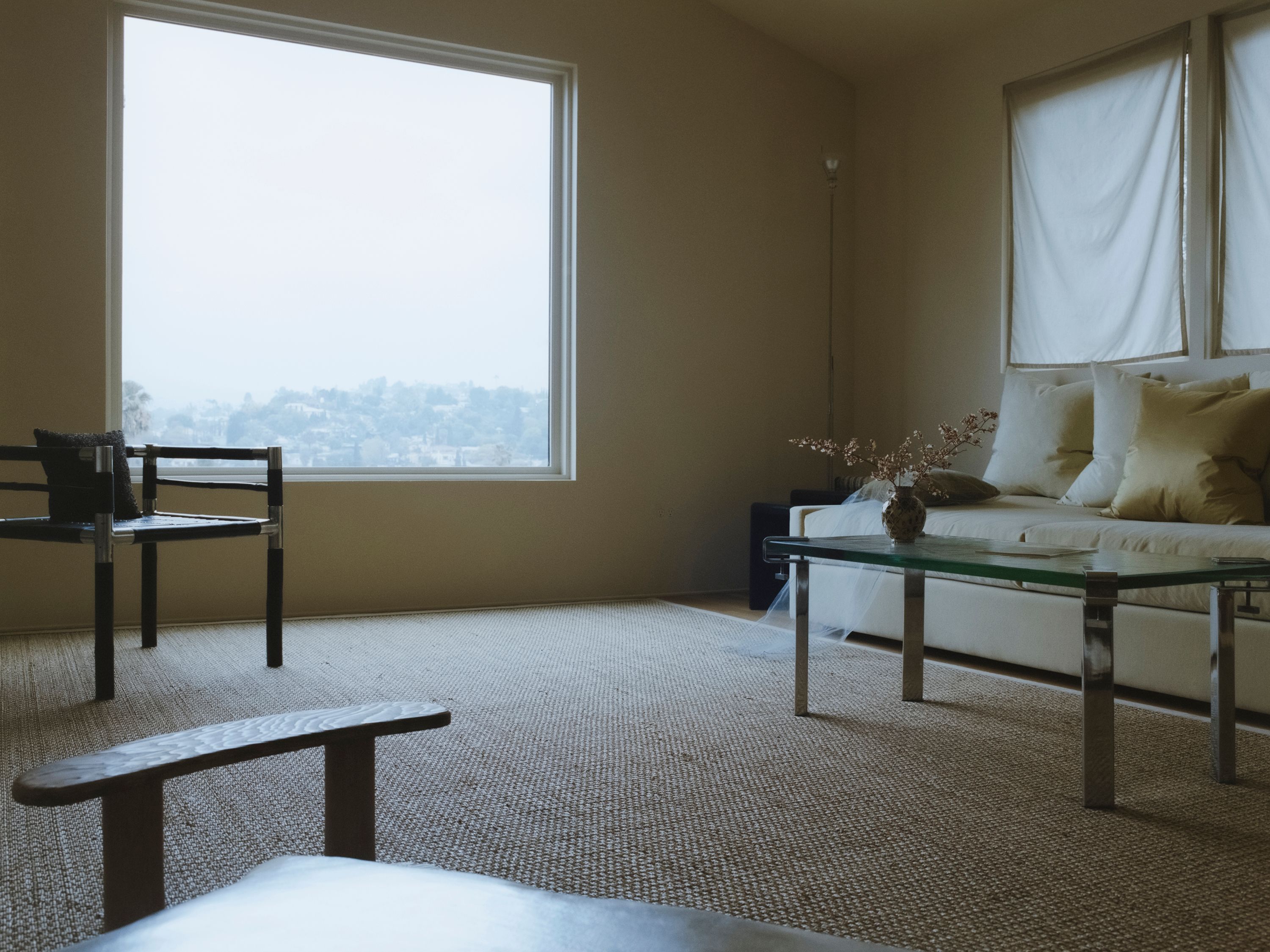 a black bamboo chair next to a large window, a coffee table in front of a green sofa,WOE, Width Over Ears