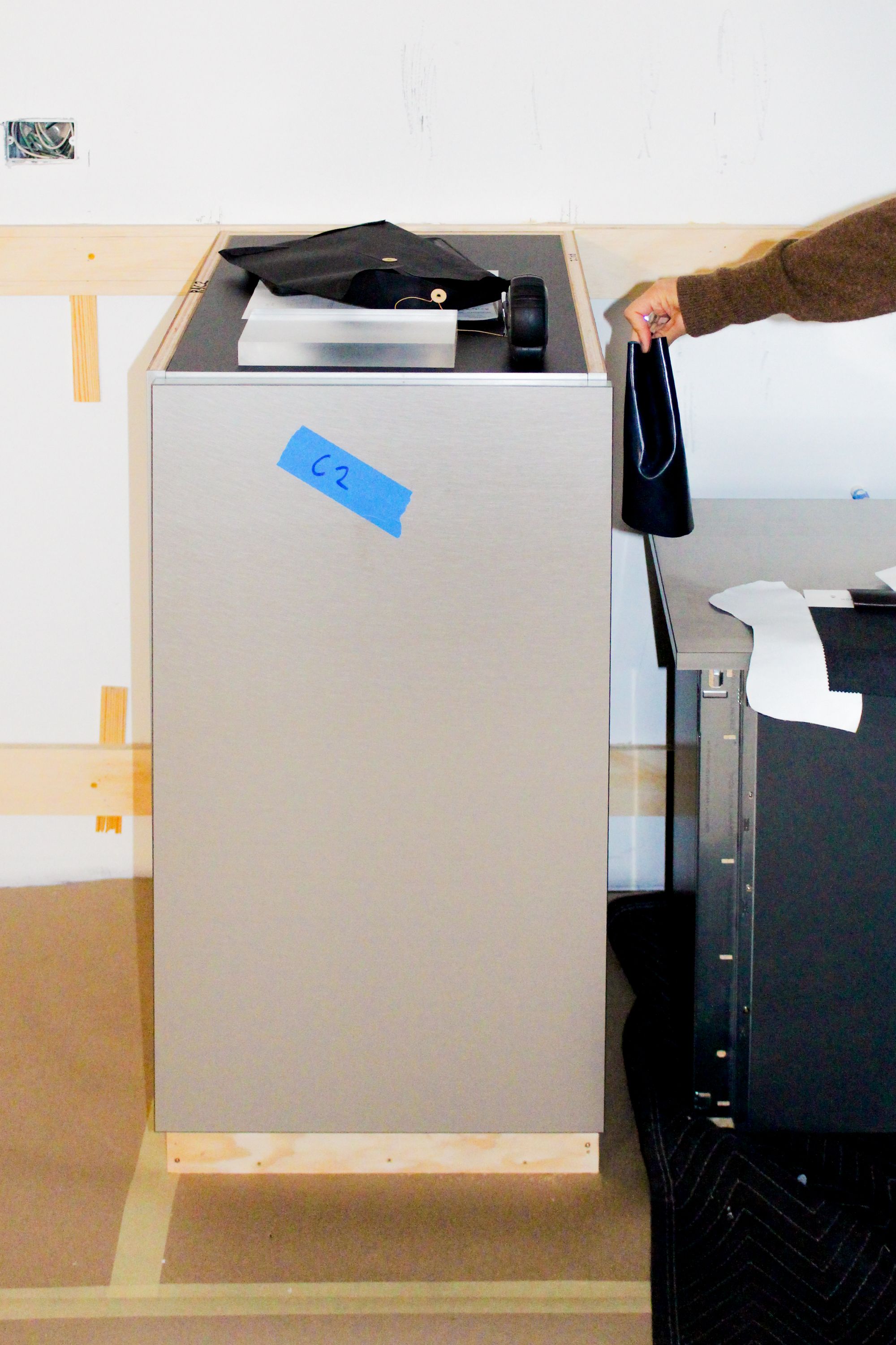 a hand holding a piece of shiny blue leather next to a silver cabinet