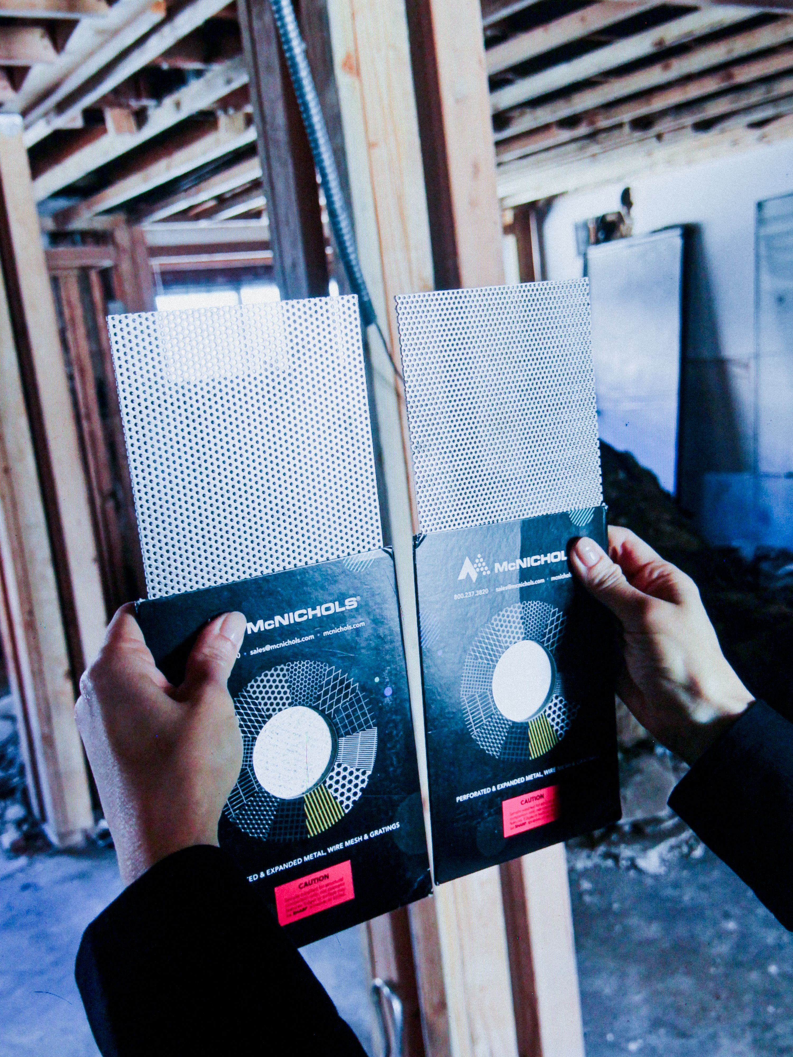 hands holding up two different types of perforated steel, WOE, Width Over Ears