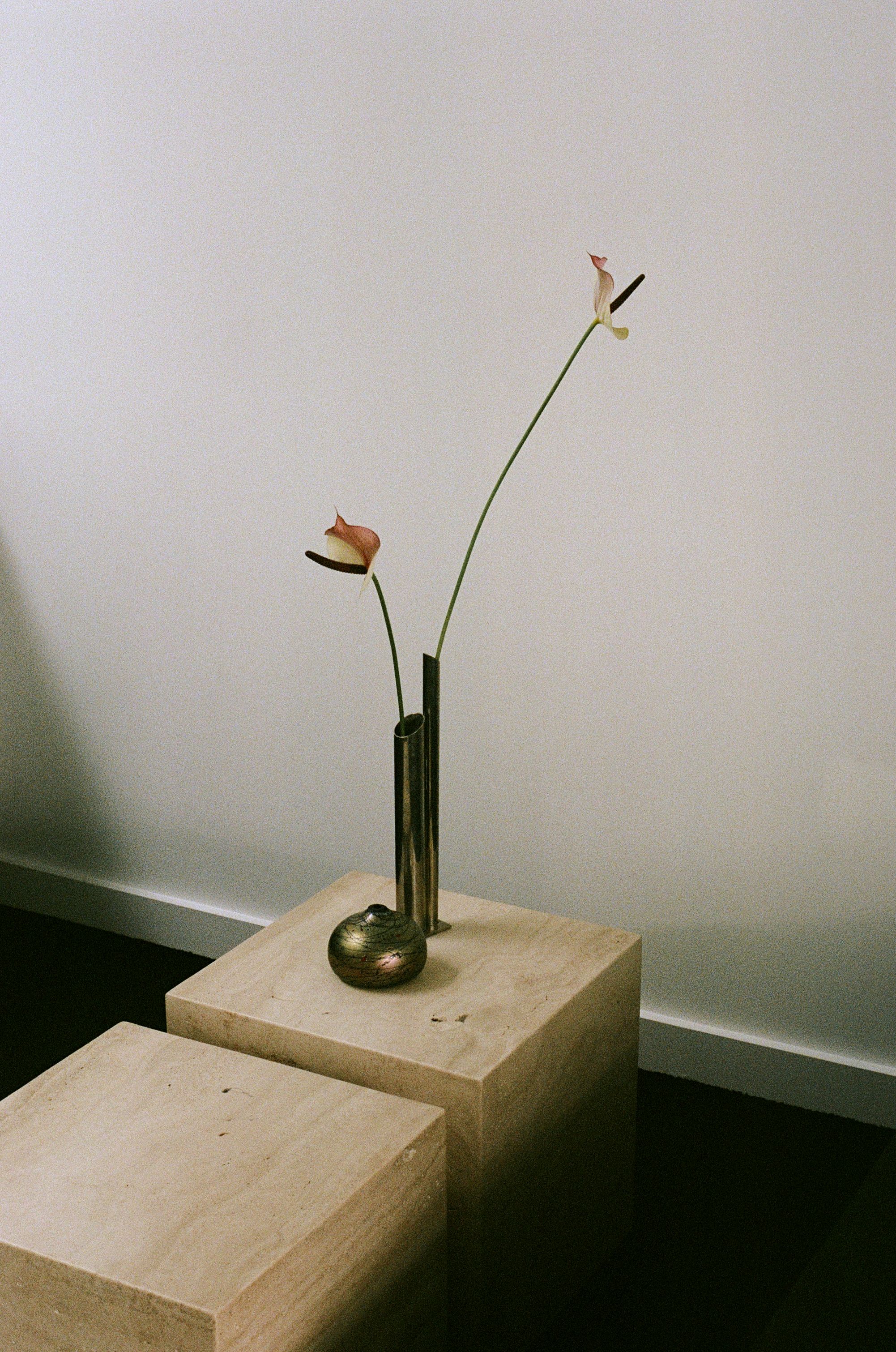 a pair of travertine blocks with a pair of vases on top and a flower arrangement