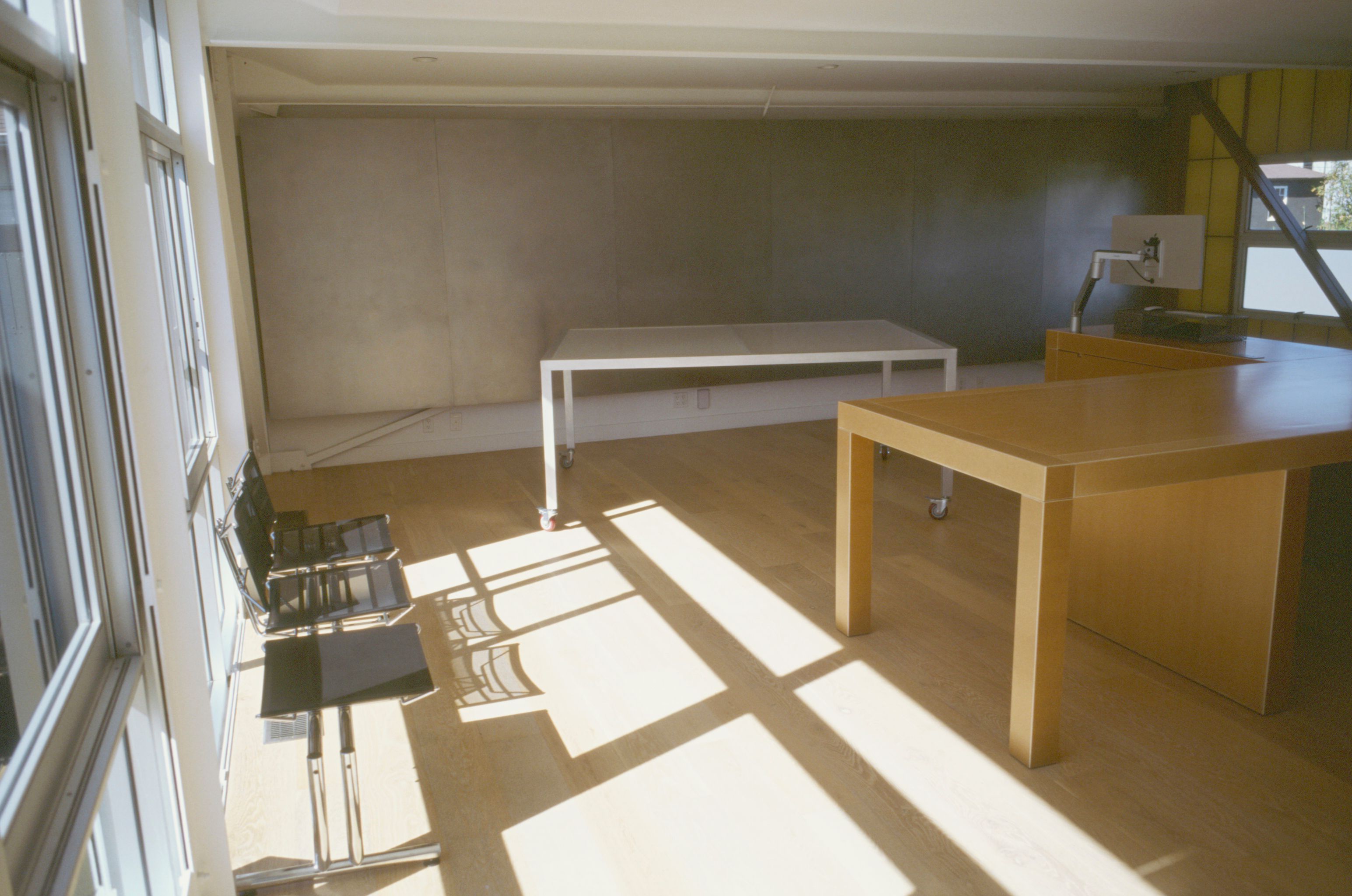 a large desk in the middle of a room with wooden floors and intense shadows