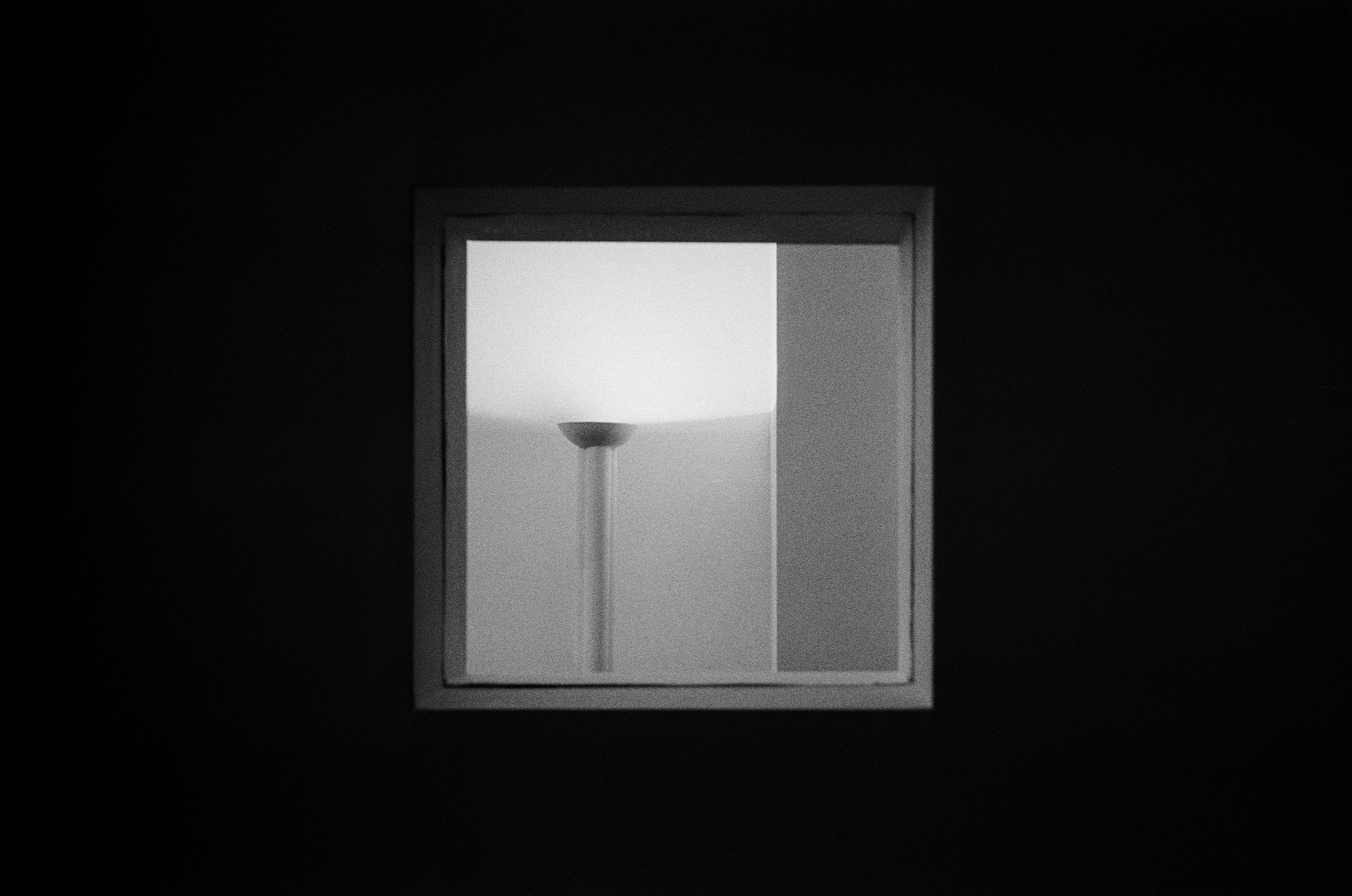 a black and white image of a white light fixture shining light up