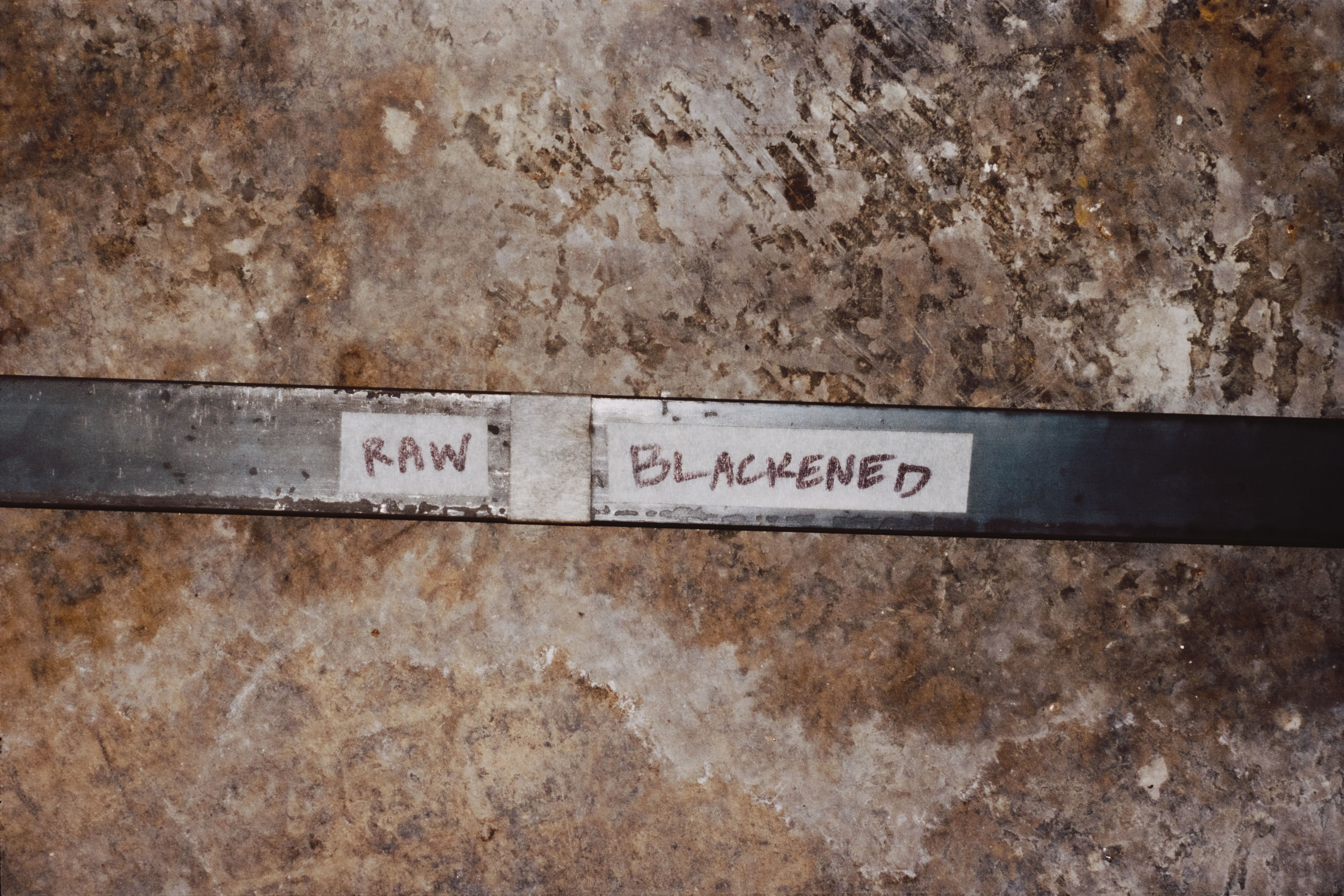 a long piece of steel on a concrete ground with the words "RAW" and "BLACKENED" written on tape,, WOE, Width Over Ears