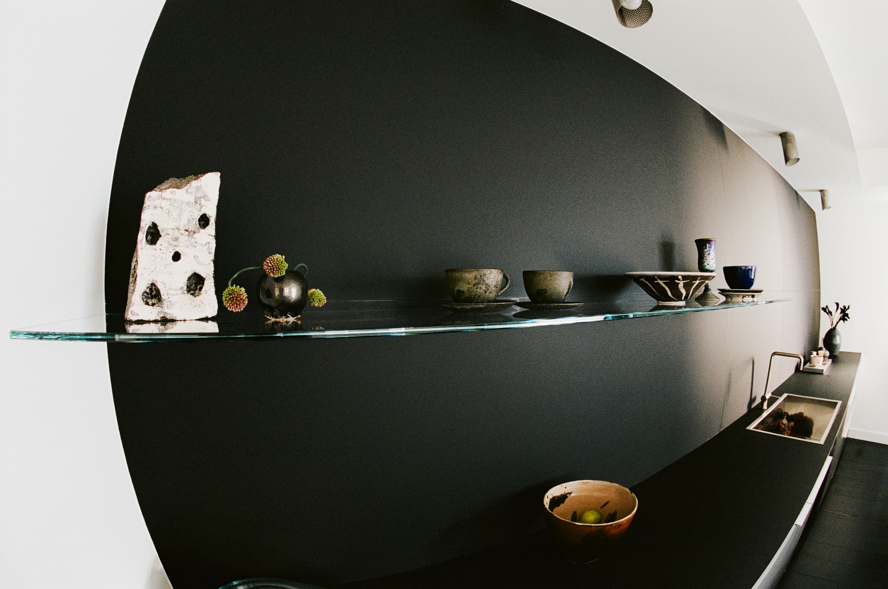 a glass kitchen shelf with cups and bowls on it