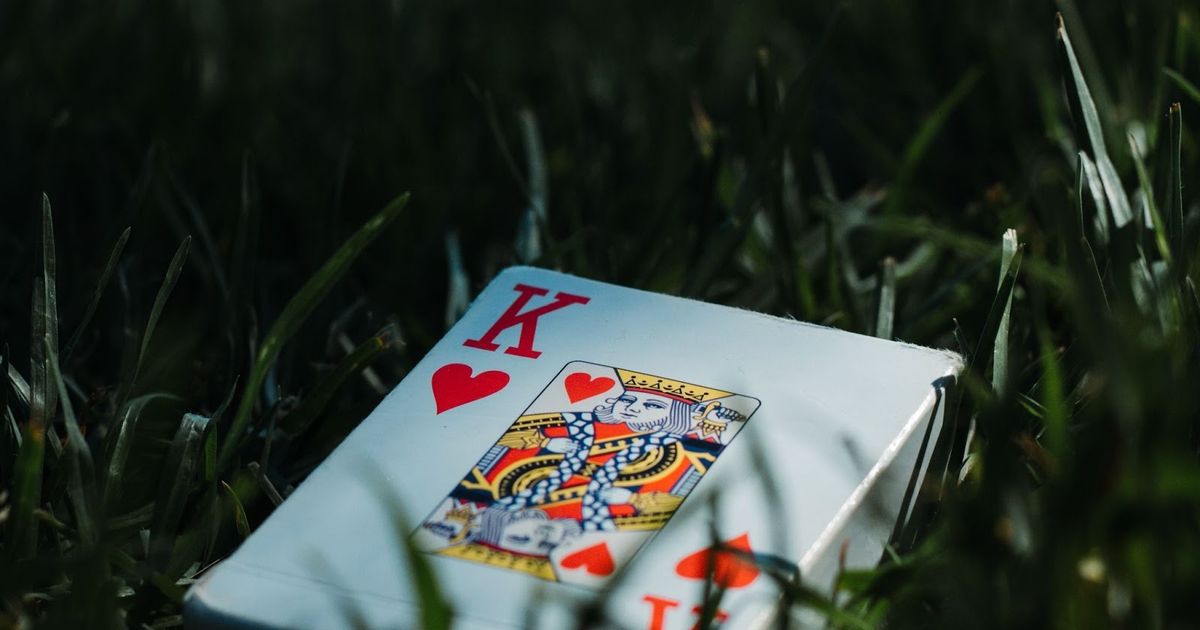 King and Queen of hearts playing cards displayed on white surface surrounded by grass blades