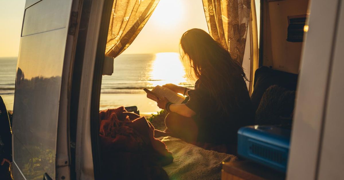 Woman enjoying a beautiful view inside of a camper in front of the beach
